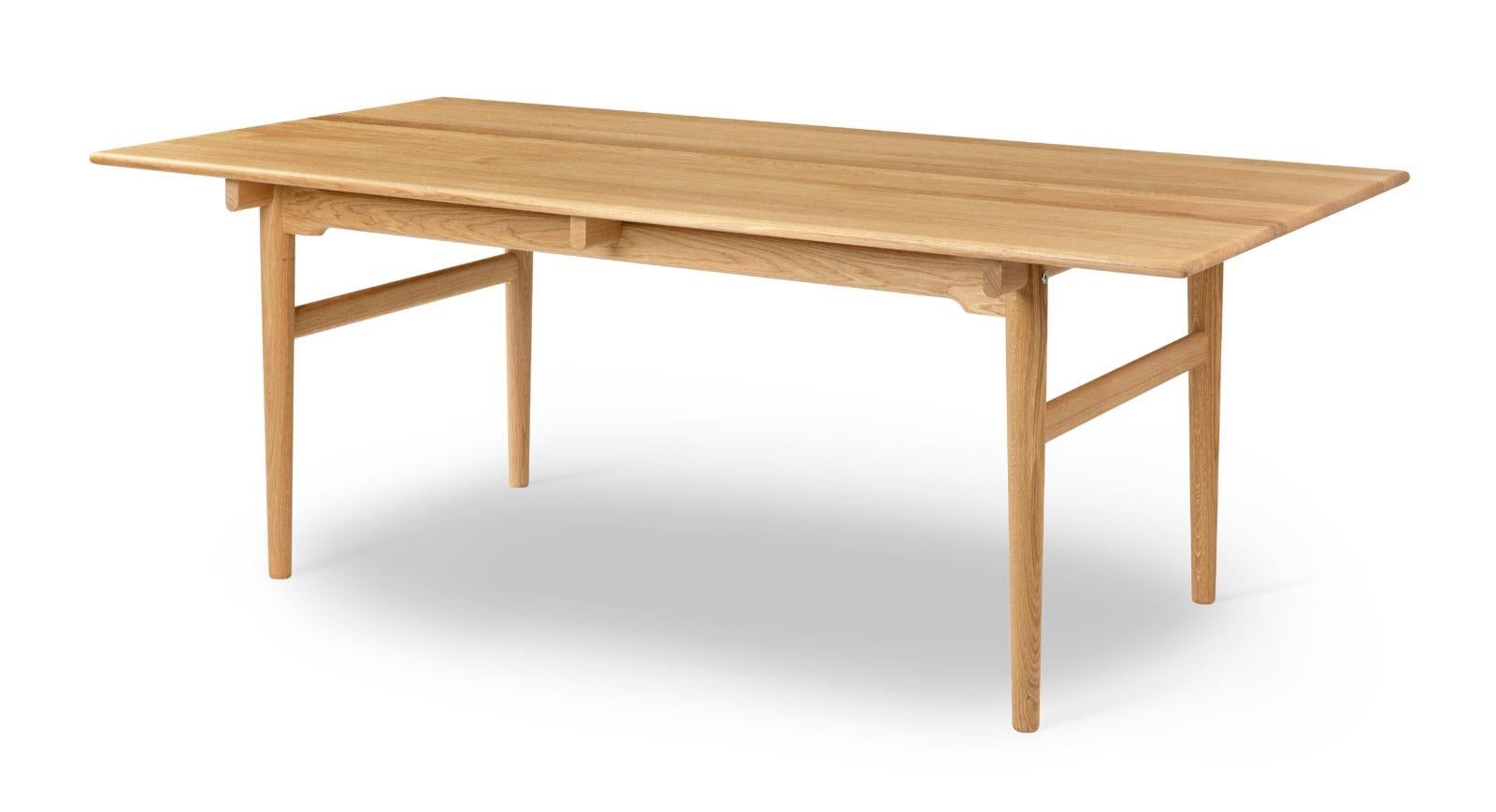 La table à manger CH327 pour 6 personnes de Hans J. Wegner, datant de 1962, présente un design inhabituel où le plateau semble presque flotter. Le plateau de la table est en bois massif avec des bords adoucis et des pieds arrondis qui se