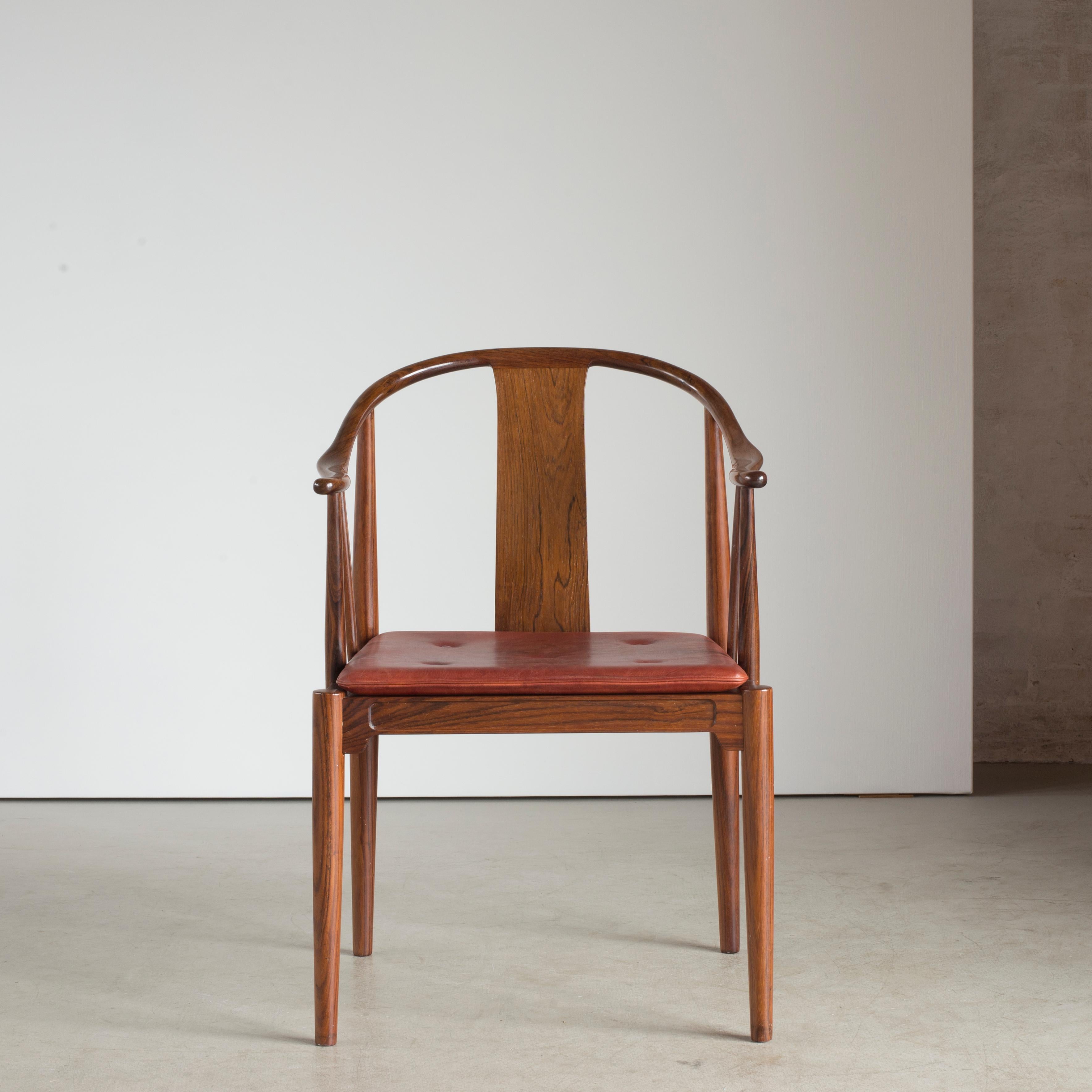 Hans J. Wegner Chinesischer Stuhl aus Palisanderholz. Lose Sitzkissen mit Leder bezogen, mit Knöpfen versehen. Ausgeführt von Fritz Hansen.

Rückseite mit Papieretikett Fritz Hansen, DÄNEMARK.

 