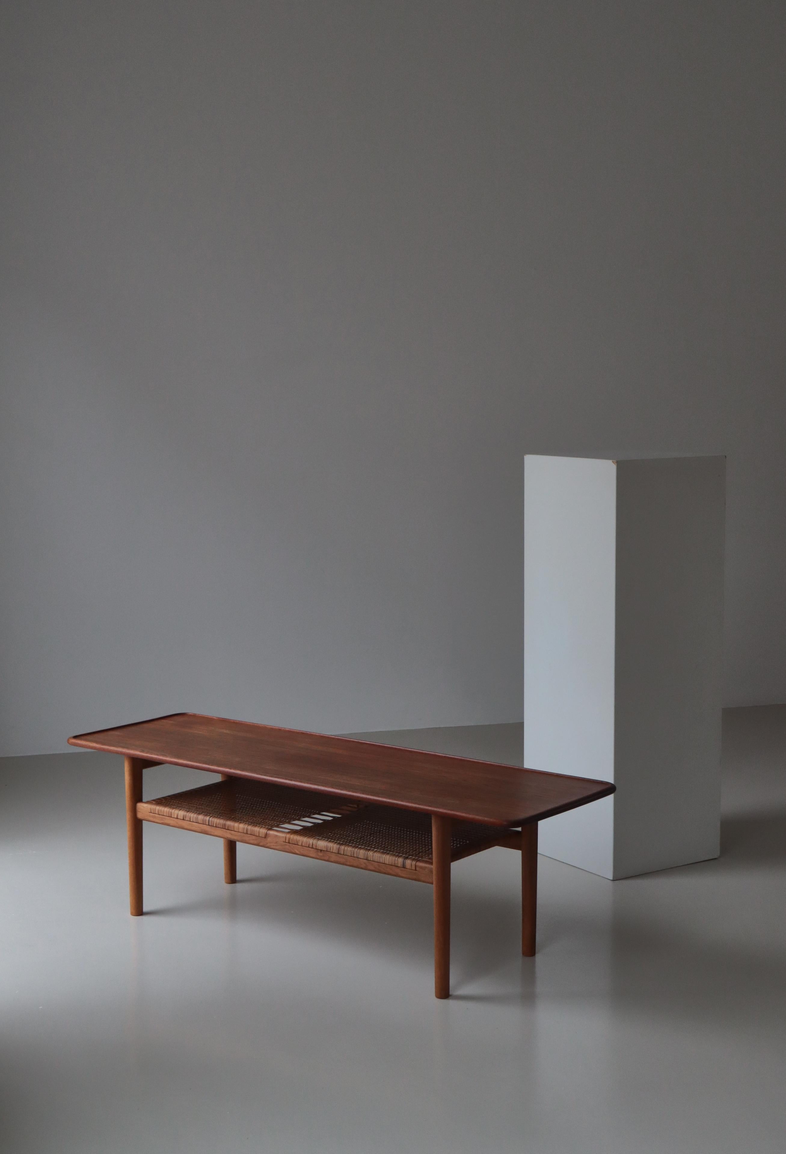 Iconic and rare Hans J. Wegner coffee table in solid teakwood, oak and rattan cane made by cabinetmaker Andreas Tuck, Odense, Denmark. This model 