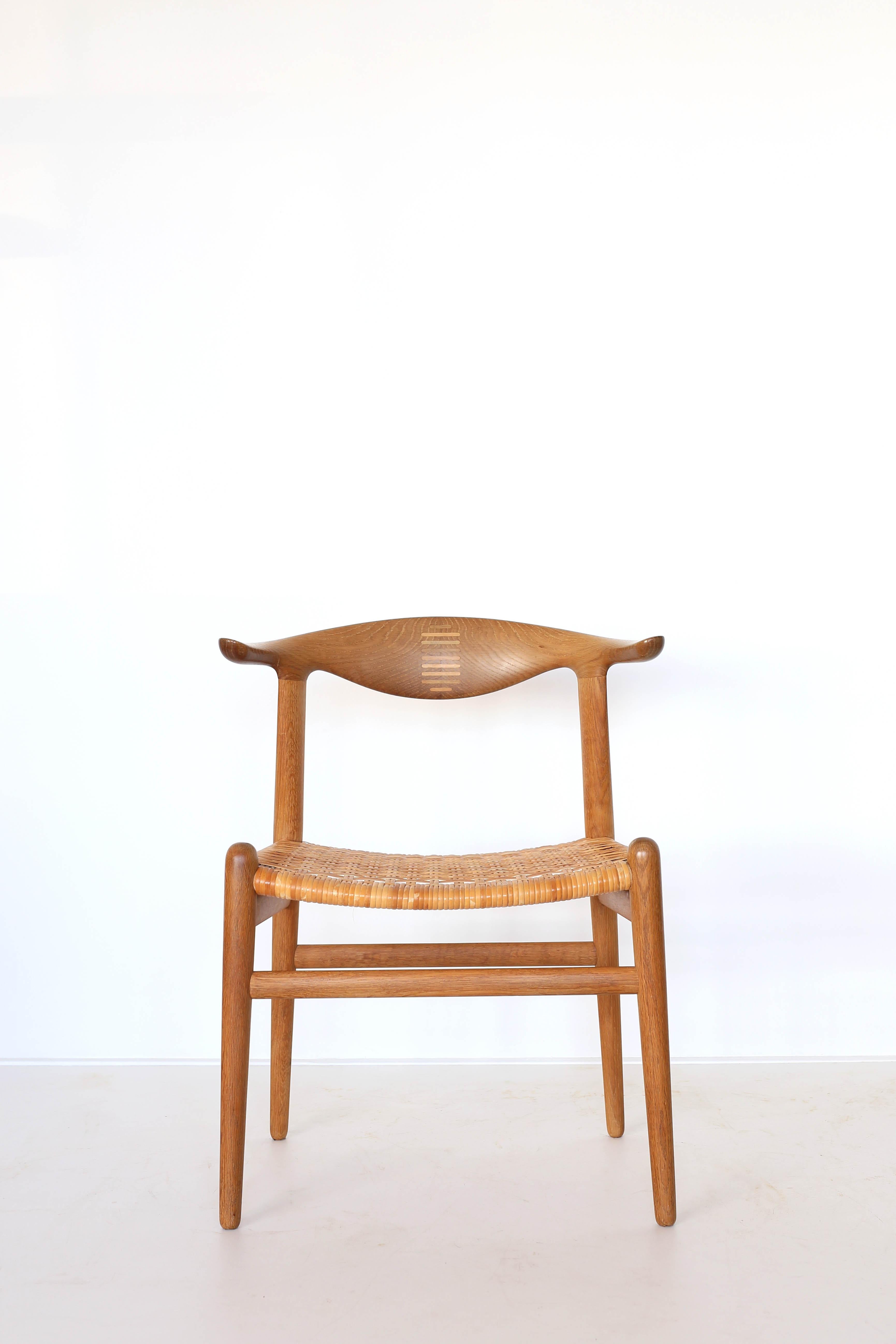 Chaise 'Cow-horn' de Hans J. Wegner en chêne patiné avec assise en cannage d'origine. 

Conçu en 1952 et exécuté chez l'ébéniste Johannes Hansen, Danemark, modèle JH505 avec marque de fabrication. 

Bel état patiné d'origine. 

