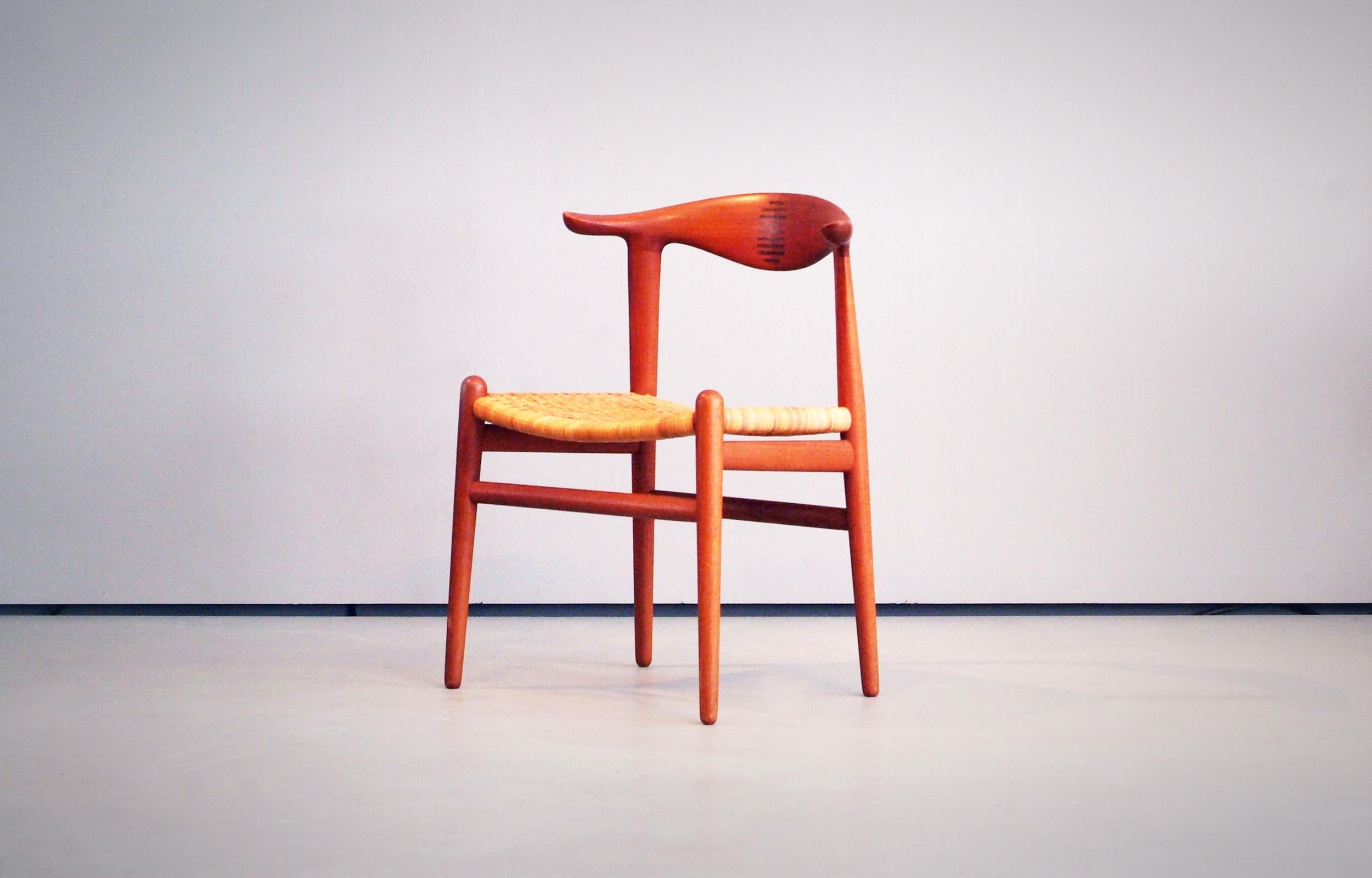 Hans J. Wegner cow horn chair made by Johannes Hansen, Denmark. Beautiful grained teak frame with inlays of Brazilian rosewood and original cane seat.

A few broken cane stripes (almost invisible) in the front part of the seat (pictured) that could