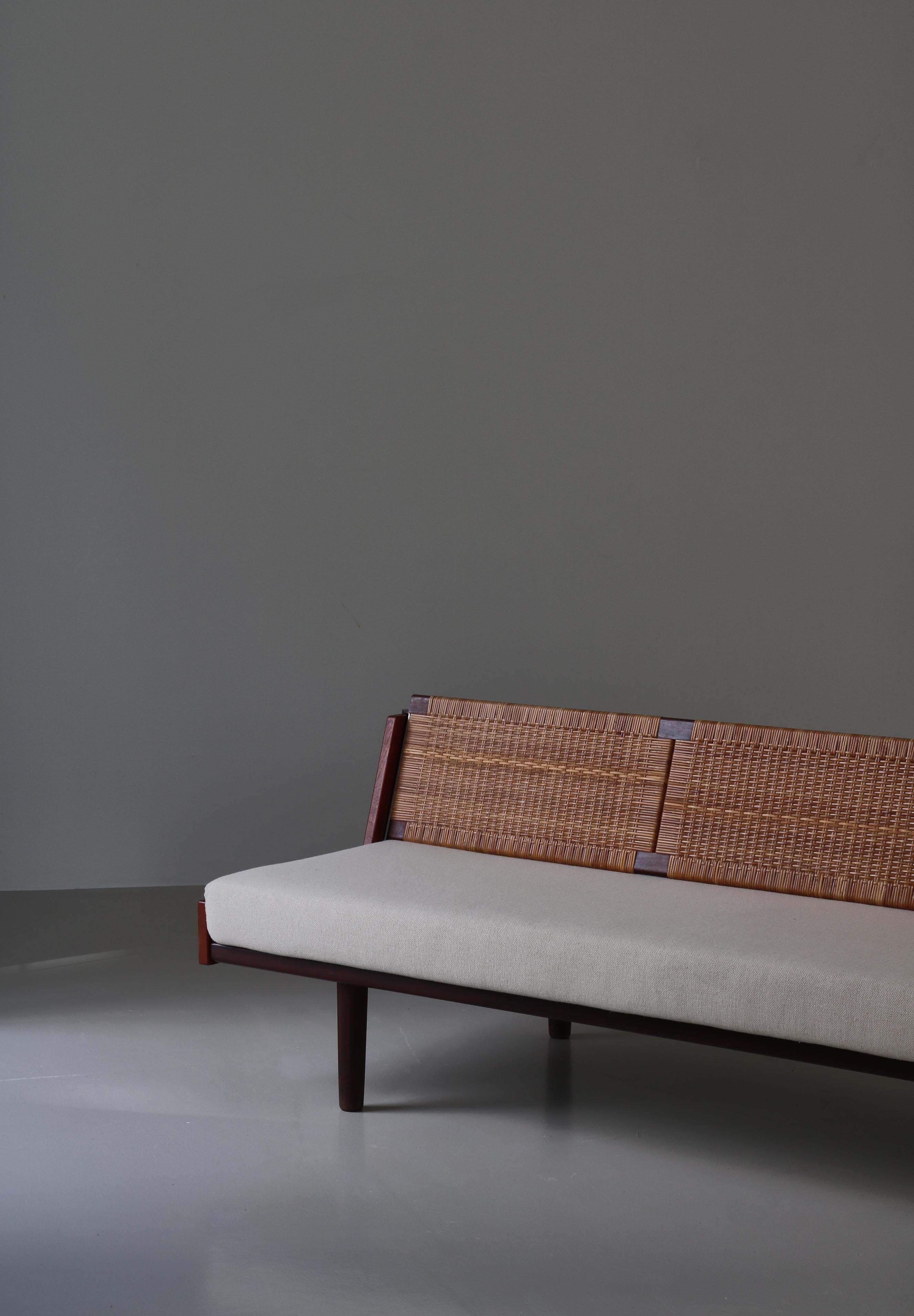 Conçu par Hans Wegner pour GETAMA, cet étonnant lit de jour/canapé convertible est doté d'une structure en teck patiné et d'un dossier en rotin tressé qui révèle un espace caché pour les couvertures, les oreillers, etc. Le modèle GE-7 a été conçu