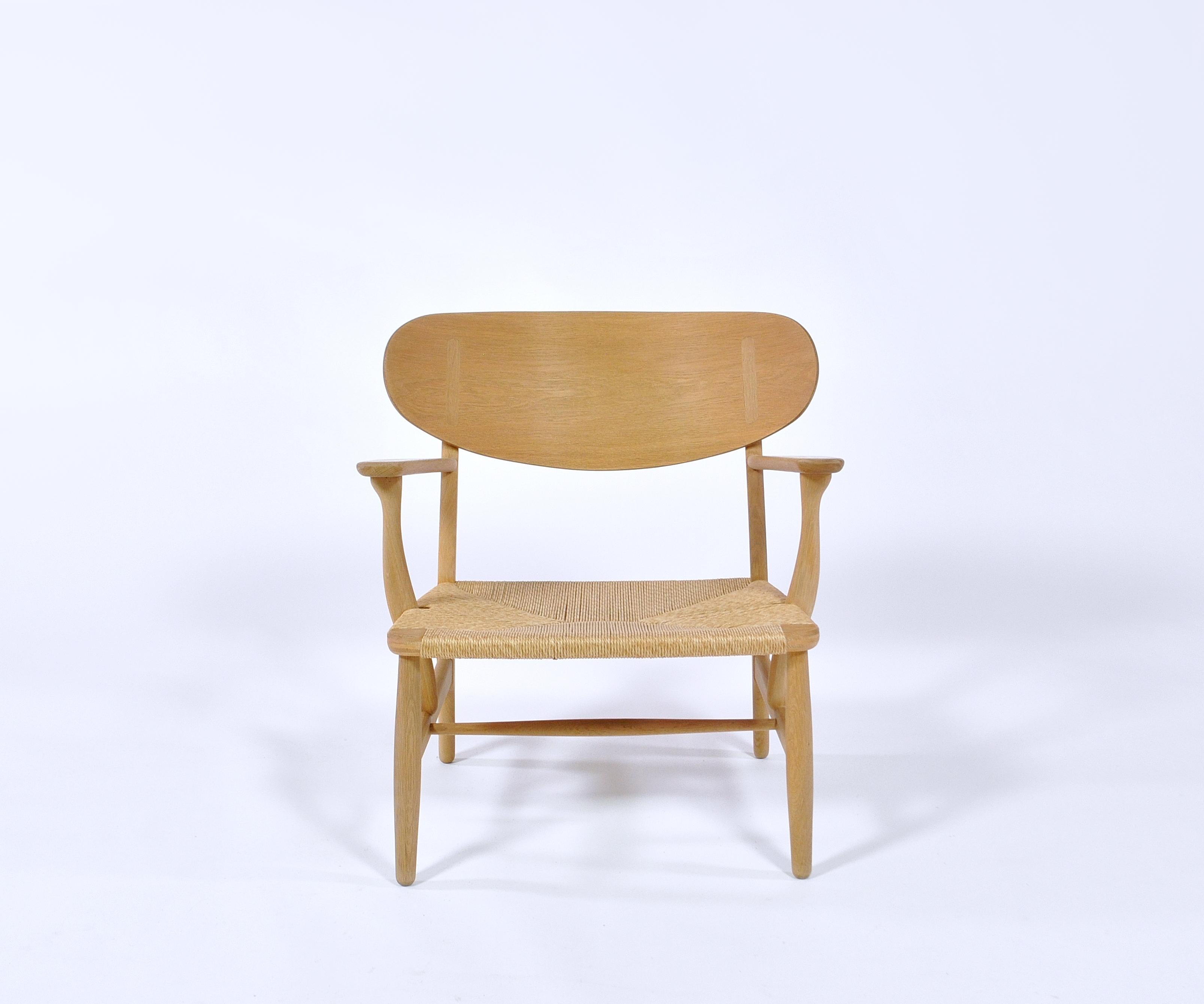 Hans J. Wegner´s iconic model CH-22 oak lounge chair for Carl Hansen & Son, Denmark. Designed in the early 1950s. Beautiful vintage production example with original label underneath the arm and in very good original condition. Beautiful wood grain.
