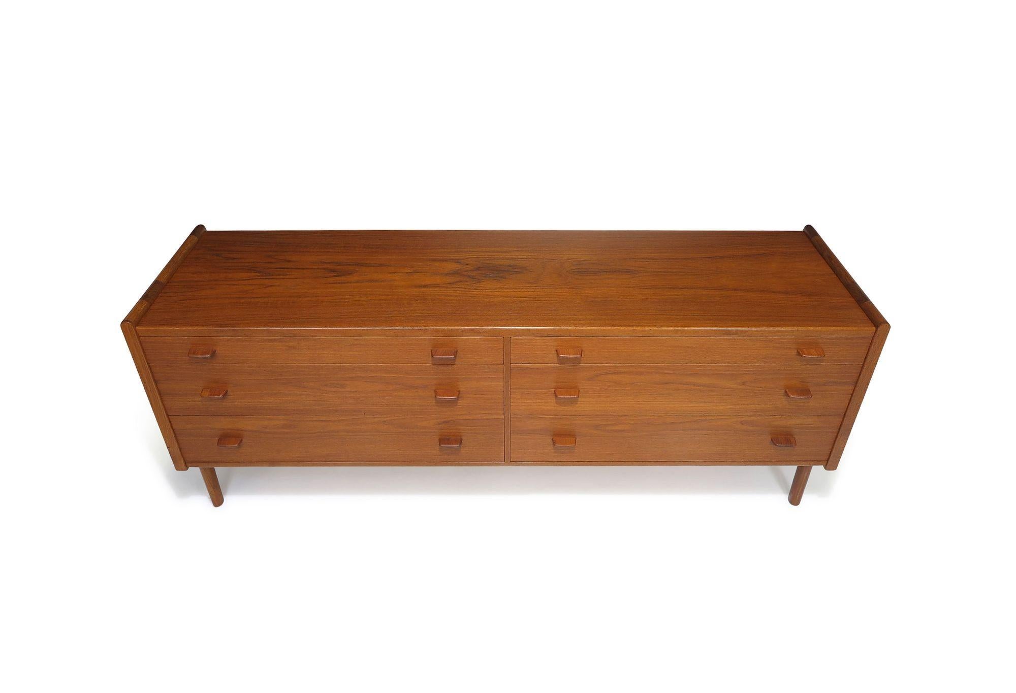 Teak double dresser designed by Hans Wegner for Ry Mobler, Denmark, in 1958. This finely crafted cabinet features six drawers, each adorned with sculpted pulls and birch interiors. Raised on solid teak legs, the dresser is meticulously finished on