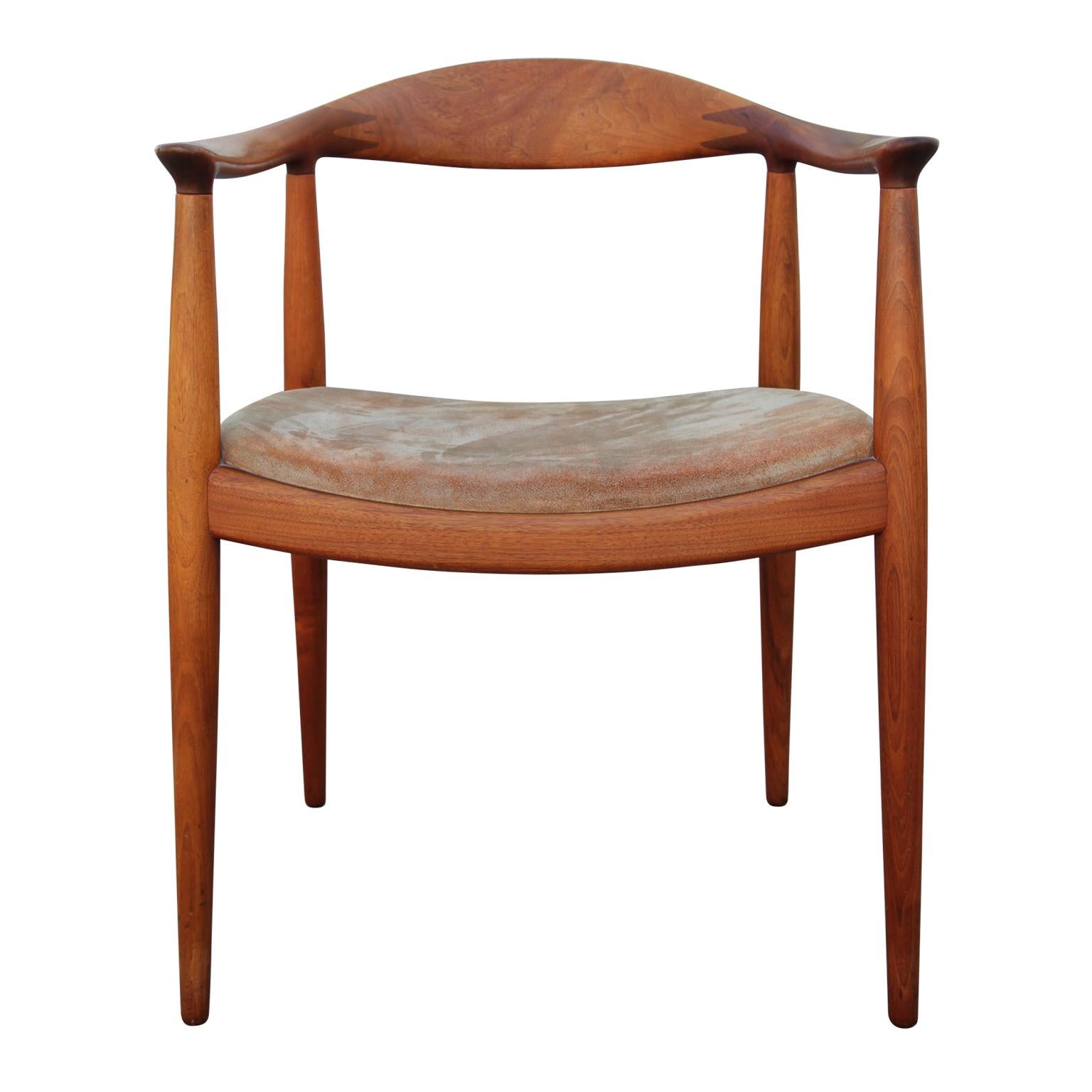 Single Mid-Century Modern dining chair by Hans Wegner for Johannes Hansen made in Denmark. The chair features a brown suede seat and a sculptural modern design. On the bottom of the chair is the makers stamp along with location of production. Teak.