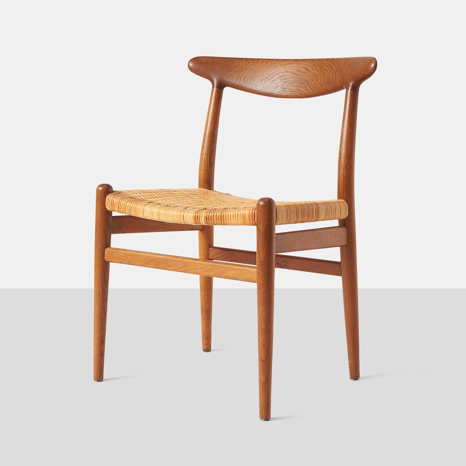 A set of five stained oak and cane dining chairs. Each chair frame is branded with the manufacturer's mark; [C.M. Madsen Fabriker Haarby Danmark Made in Denmark Design: Hans J. Wegner].



