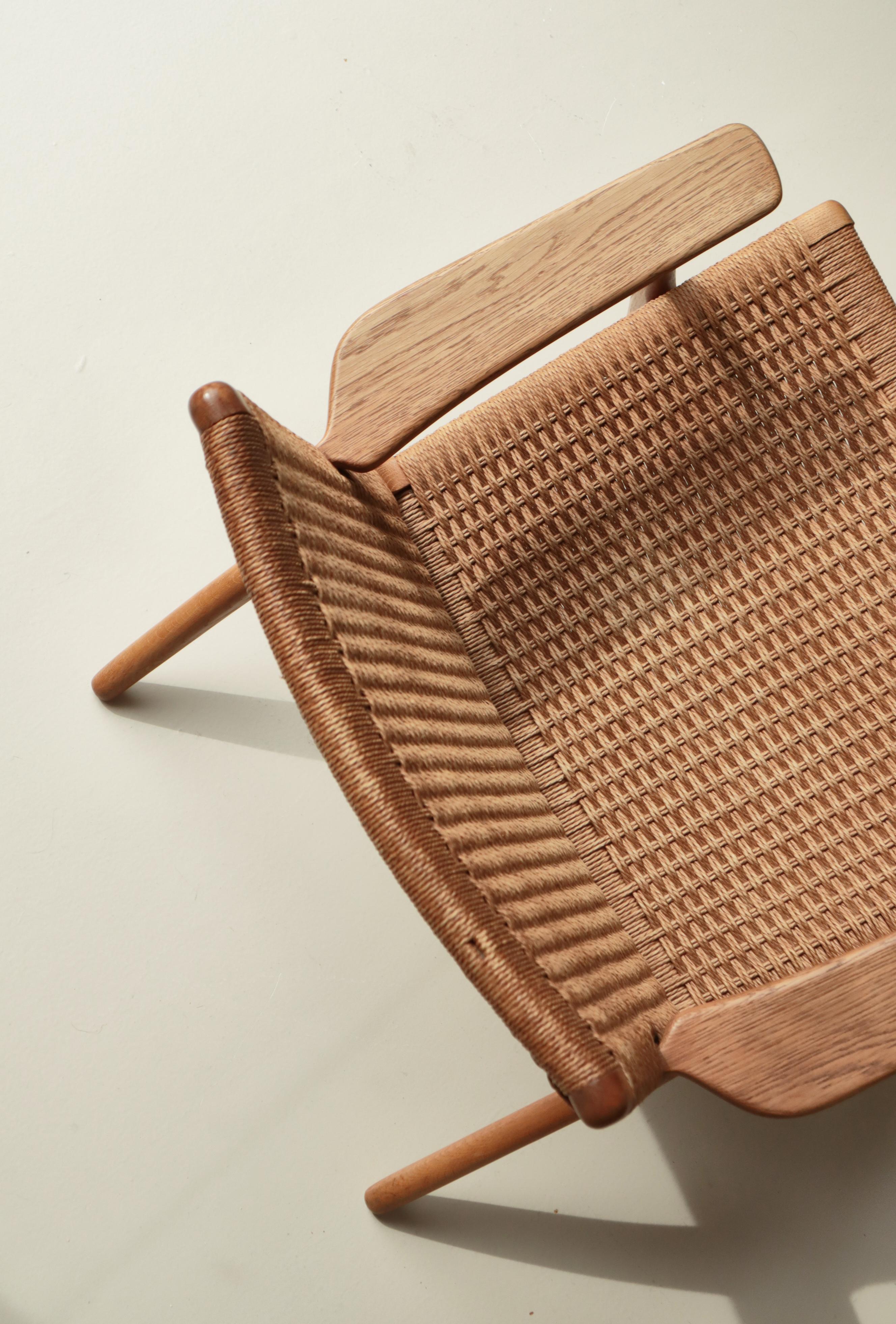 Seltener Loungesessel Modell CH25 des dänischen Designers Hans J. Wegner für Carl Hansen & Son aus Eichenholz und gewebter Papierkordel. Der CH25 ist einer der ersten vier Stühle, die Hans J. Wegner zu Beginn der 1949 begonnenen Collaboration für