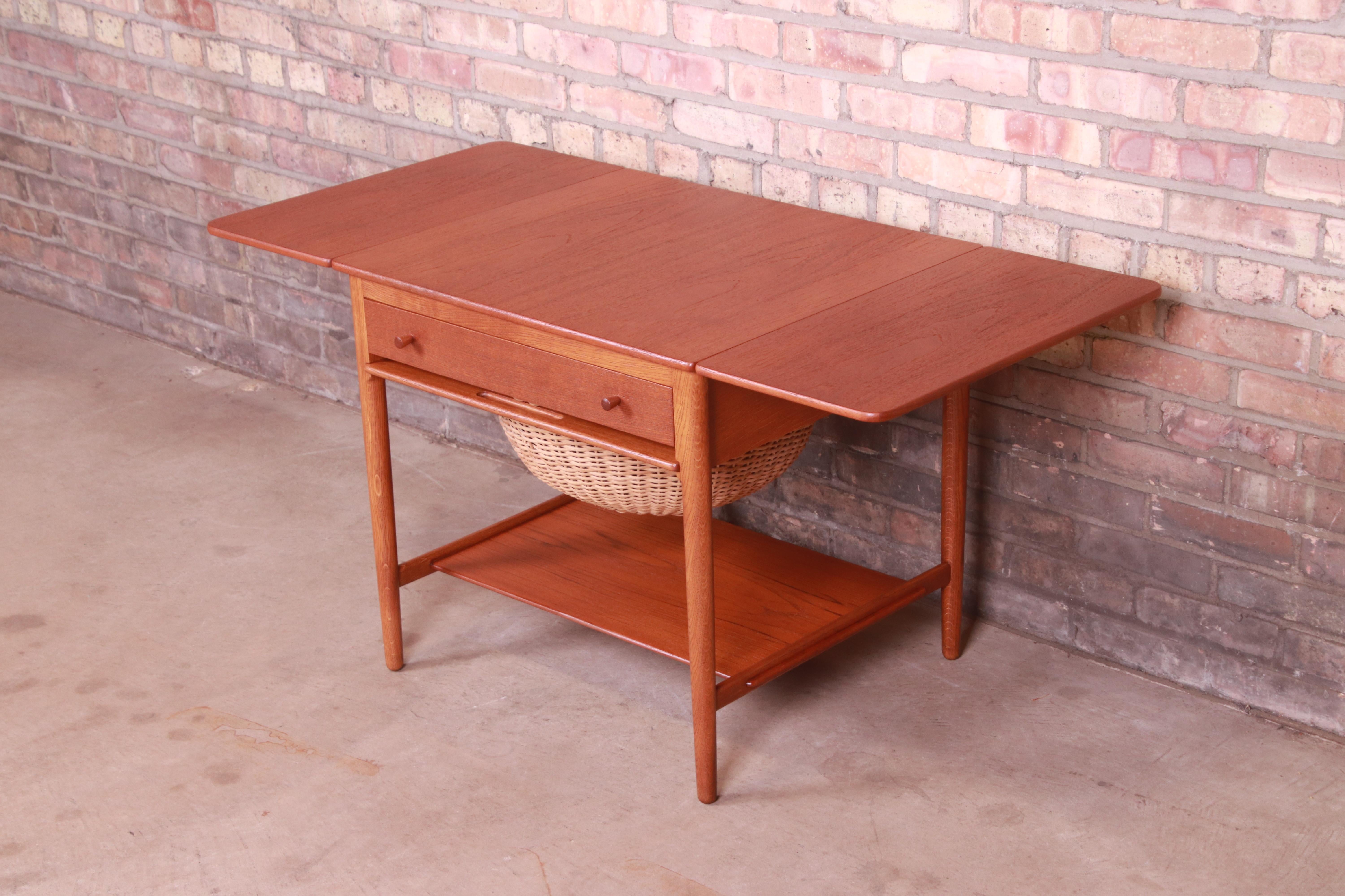 A rare and exceptional Danish Modern drop-leaf sewing table

By Hans J. Wegner for Andreas Tuck, Model AT-33

Denmark, 1950s

Solid teak and oak, with a multi-compartment drawer and hand-woven rattan basket for knitting.

Measures: 26.25