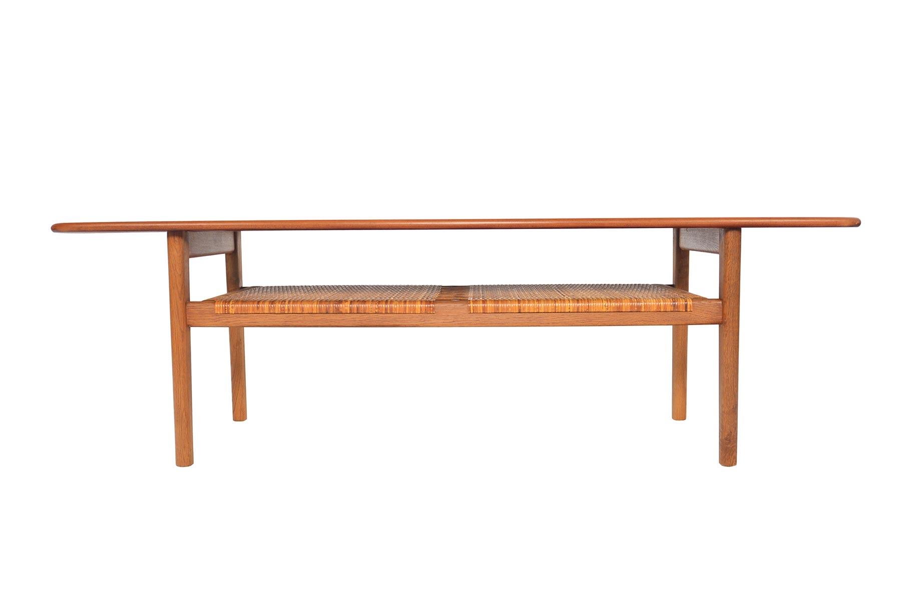A timeless design for any decor, this amazing coffee table was designed by Hans J. Wegner for Andreas Tuck in the 1950s. Table surface features a raised lip. Table stands on oak quarter- sawn base with original hand- caned rack. In excellent