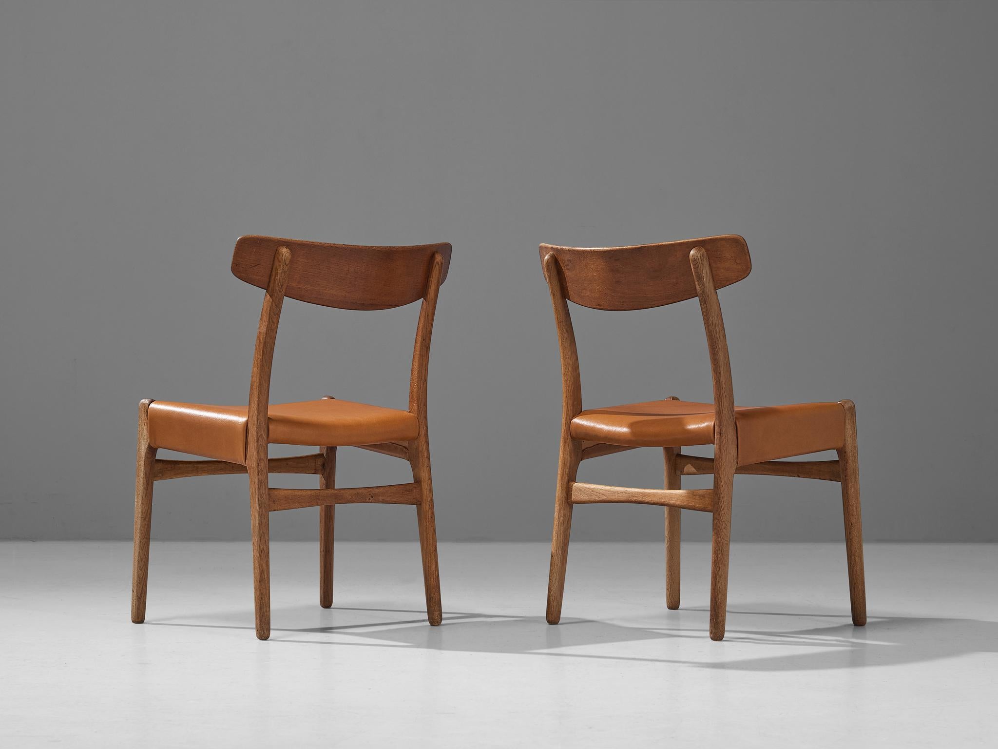 Hans J. Wegner for Carl Hansen & Søn, pair of dining chairs model ‘C23’, oak, teak, cognac leather, Denmark, designed in 1950 

The chair model ‘C23’ features sophisticated details that characterize Wegner’s well-known designs. Per example, note the