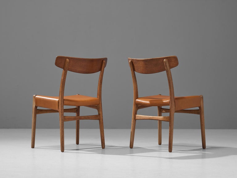 Hans J. Wegner for Carl Hansen & Søn, pair of four dining chairs model ‘C23’, oak, teak, cognac leather, Denmark, designed in 1950 

The chair model ‘C23’ features sophisticated details that characterize Wegner’s well-known designs. Per example,