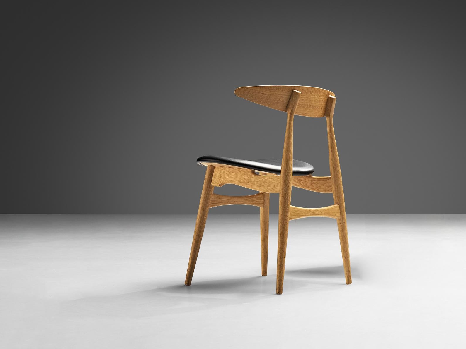 Hans J. Wegner for Carl Hansen & Søn, dining chair, model 'CH 33', oak, leather, Denmark, design 1954, later production. 

Dining chair designed by Danish designer Hans J. Wegner. These chairs are upholstered in black leather. The frame is executed