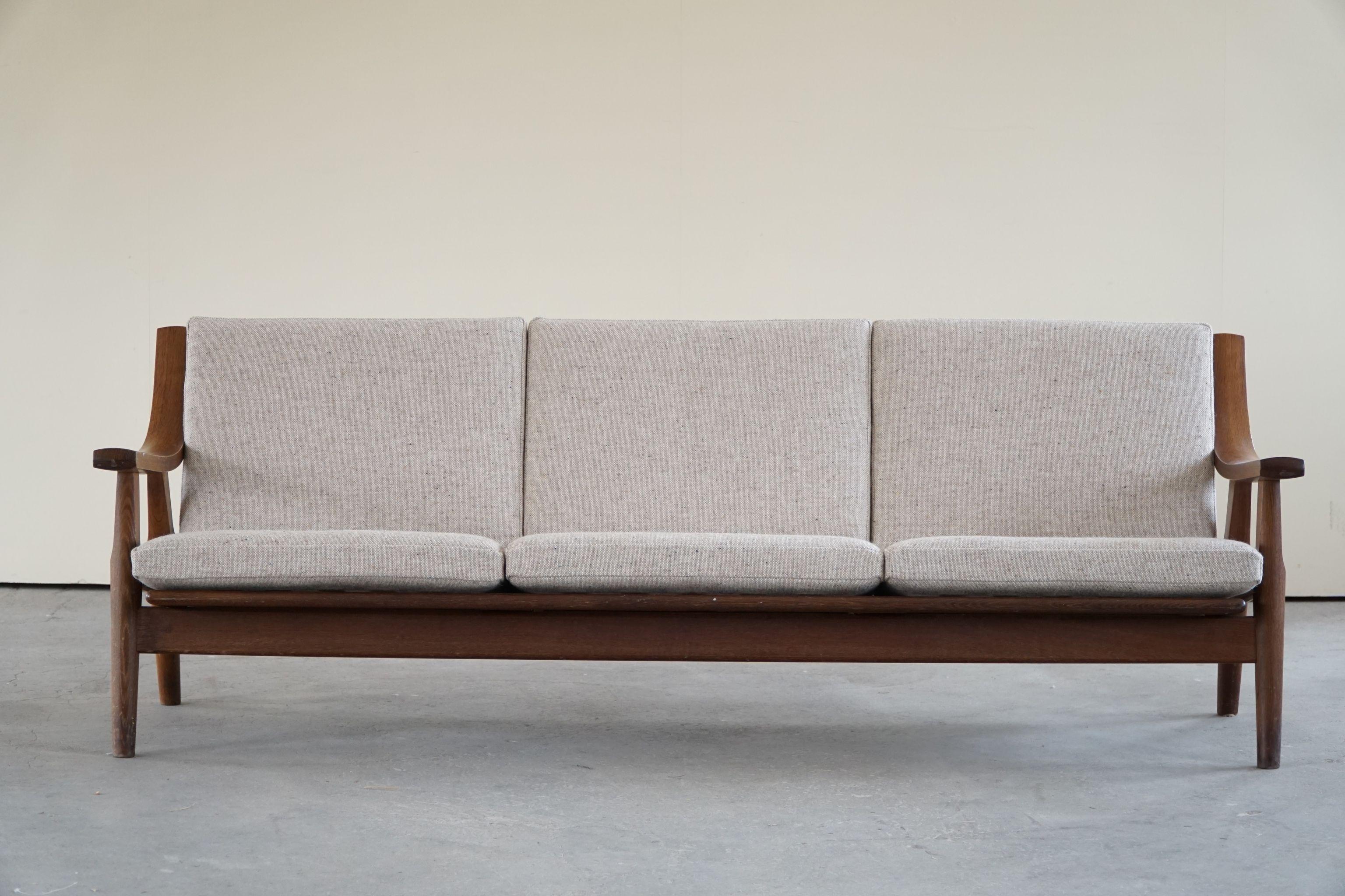 A fine example of a Classical 3-seater sofa in solid dark stained oak, reupholstered cushions in wool. Designed by Hans J. Wegner for Getama. 

This modern sofa is in a really good vintage condition.

Hans J. Wegner (Danish, 1914–2007) was a
