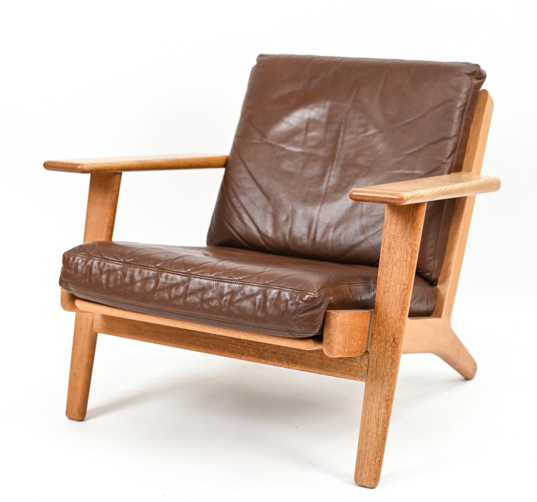 A fabulous Danish mid-century lounge chair in sturdy oak with quality construction, chocolate brown leather cushions. Designed by Hans J. Wegner for GETAMA, 1953. A testament to Wegner's fusion of comfort and style, the model GE090 lounge chair