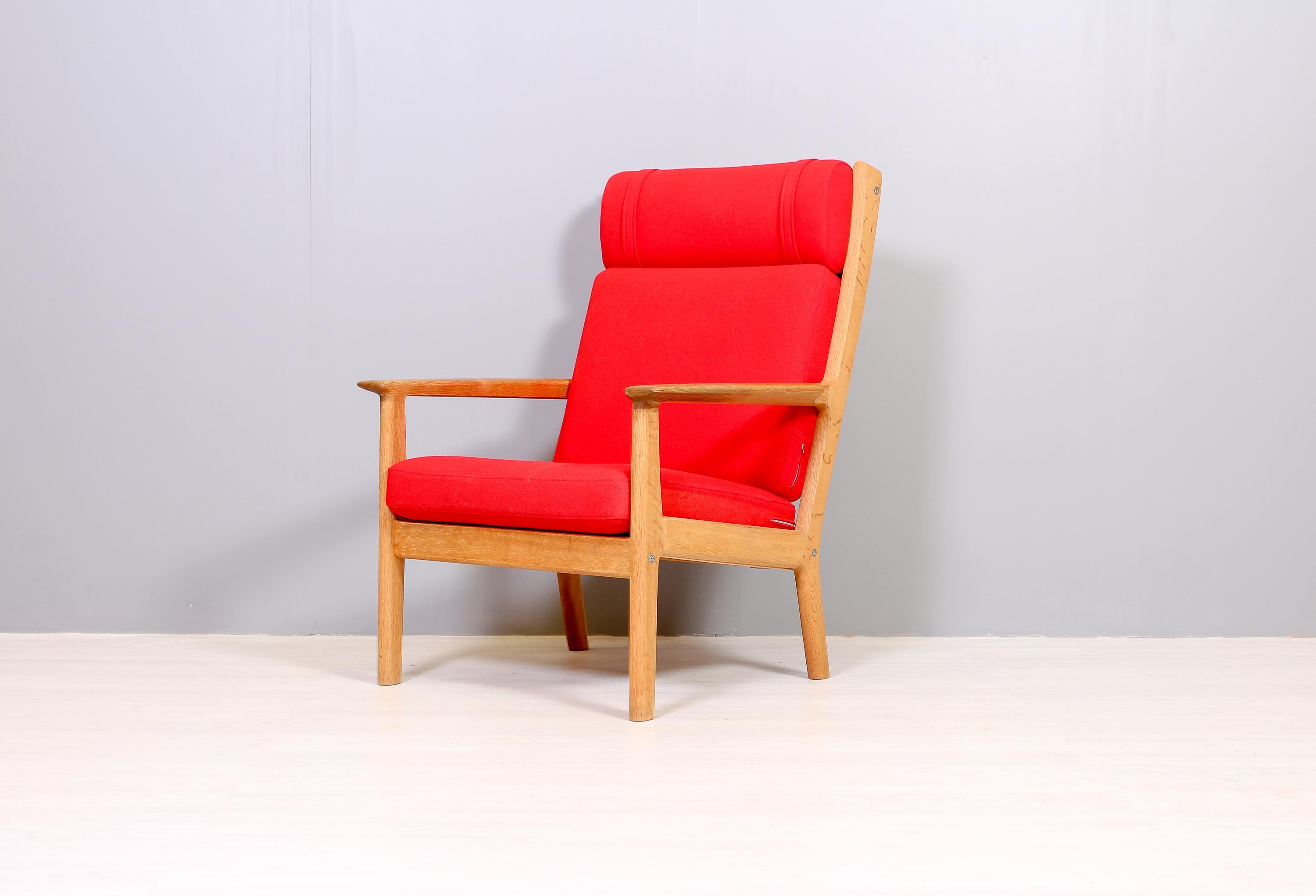 This highly comfortable lounge chair, designed by Hans J Wegner for Danish manufacturer GETAMA in the 1960s, is one of many great designs that combines comfort, quality materials and modern design. The chair is made out of solid oak and red wool