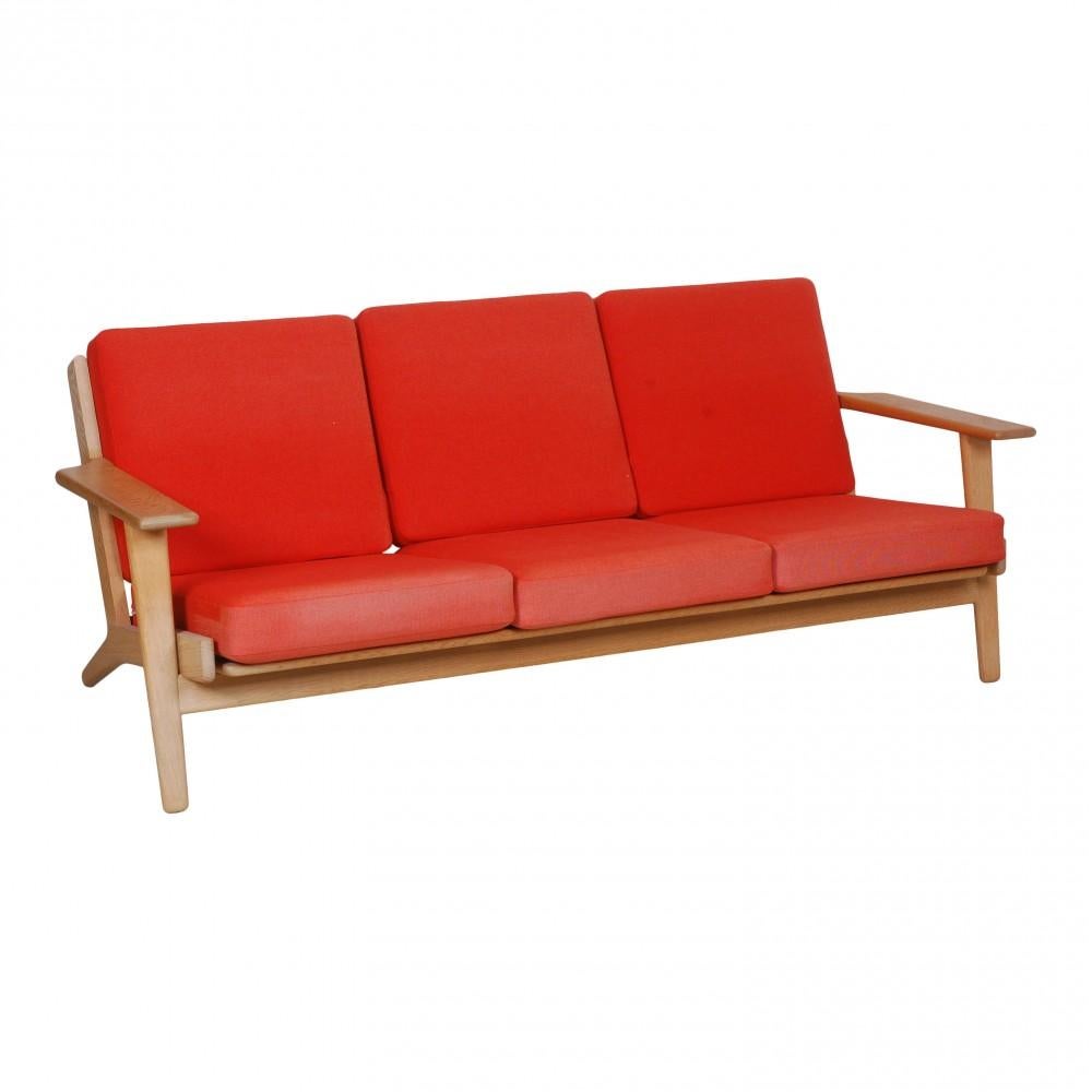 Hans Wegner Ge-290/3 Sofa mit einem Gestell aus Eichenholz und Kissen aus rotem Stoff, um 1990. Die Kissen erscheinen in der Farbe auf der Vorderseite verblasst, sind aber insgesamt in gutem Zustand.