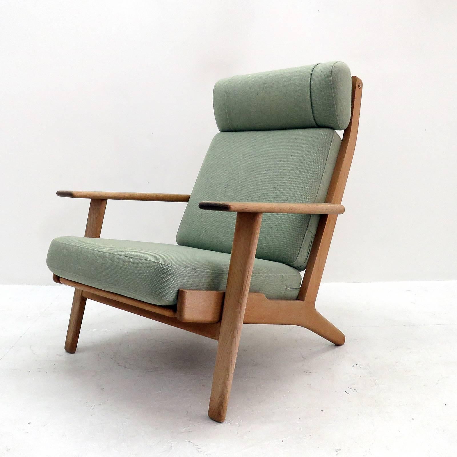 Wonderful high back lounge chair GE290 by Hans J Wegner for GETAMA, solid oak frame with nice patina and original cushions upholstered with light green wool fabric, marked.