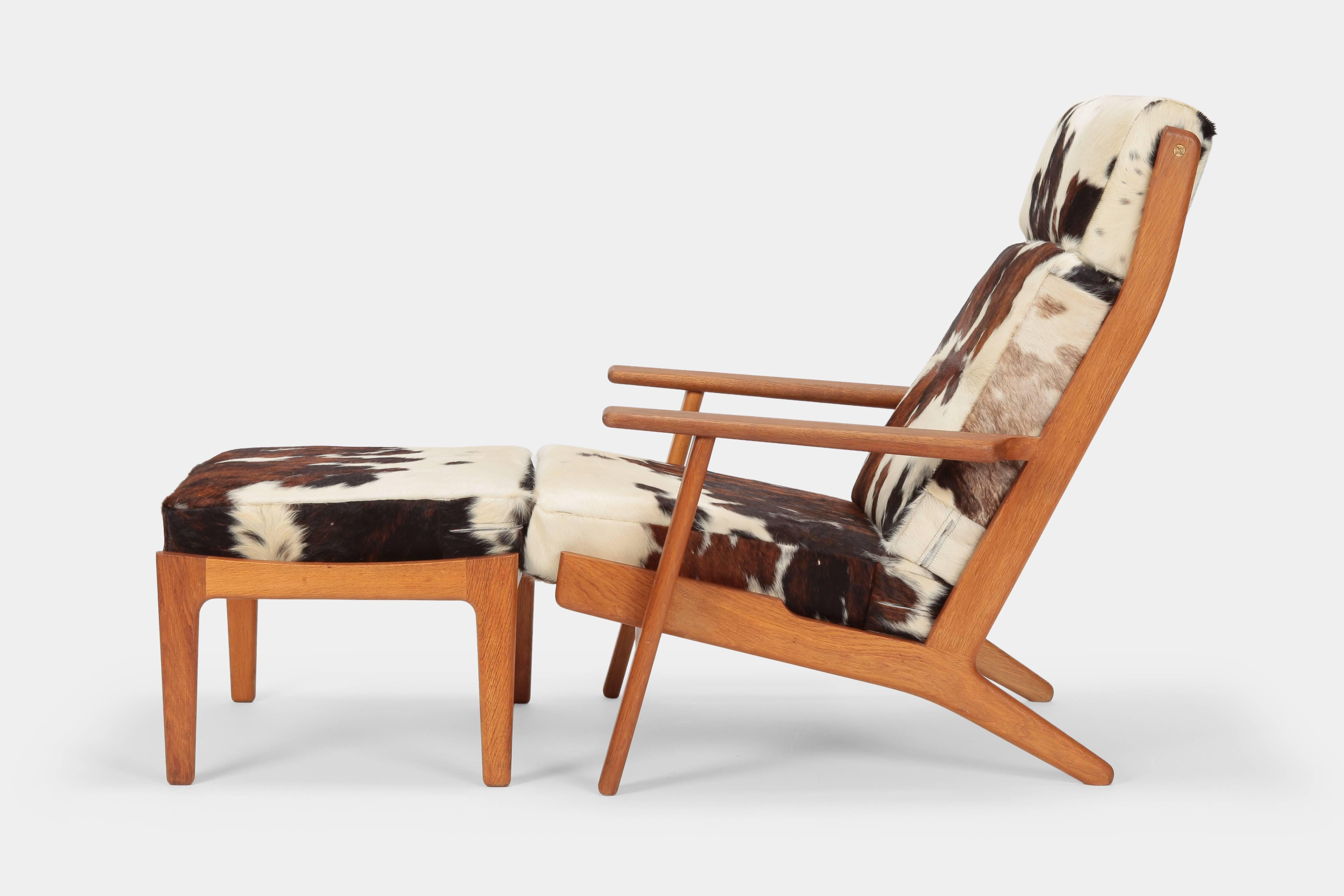 Hans J. Wegner GE-290 lounge chair manufactured by GETAMA in the 1960s in Denmark. High back lounge chair with a edgy shaped solid oak wood frame and wide armrests. The cushions are newly covered with wonderful patterned