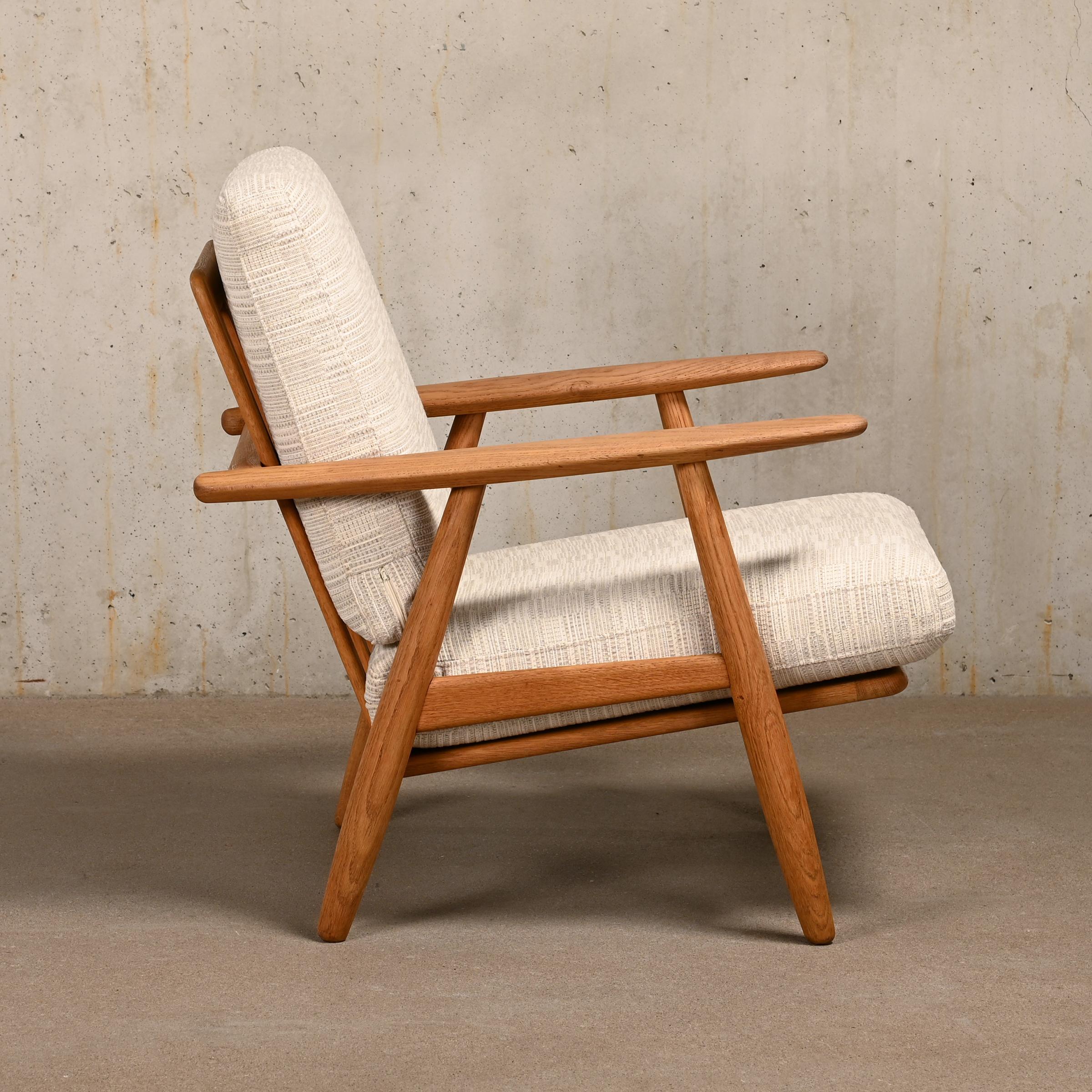 This is an early example of the Hans J. Wegner Lounge Chair model GE240 for GETAMA, Denmark. The chair is also sometimes called 'Cigar' Chair due the shape of the armrests. Beautiful aged and grained high quality oak wooden frame in very good
