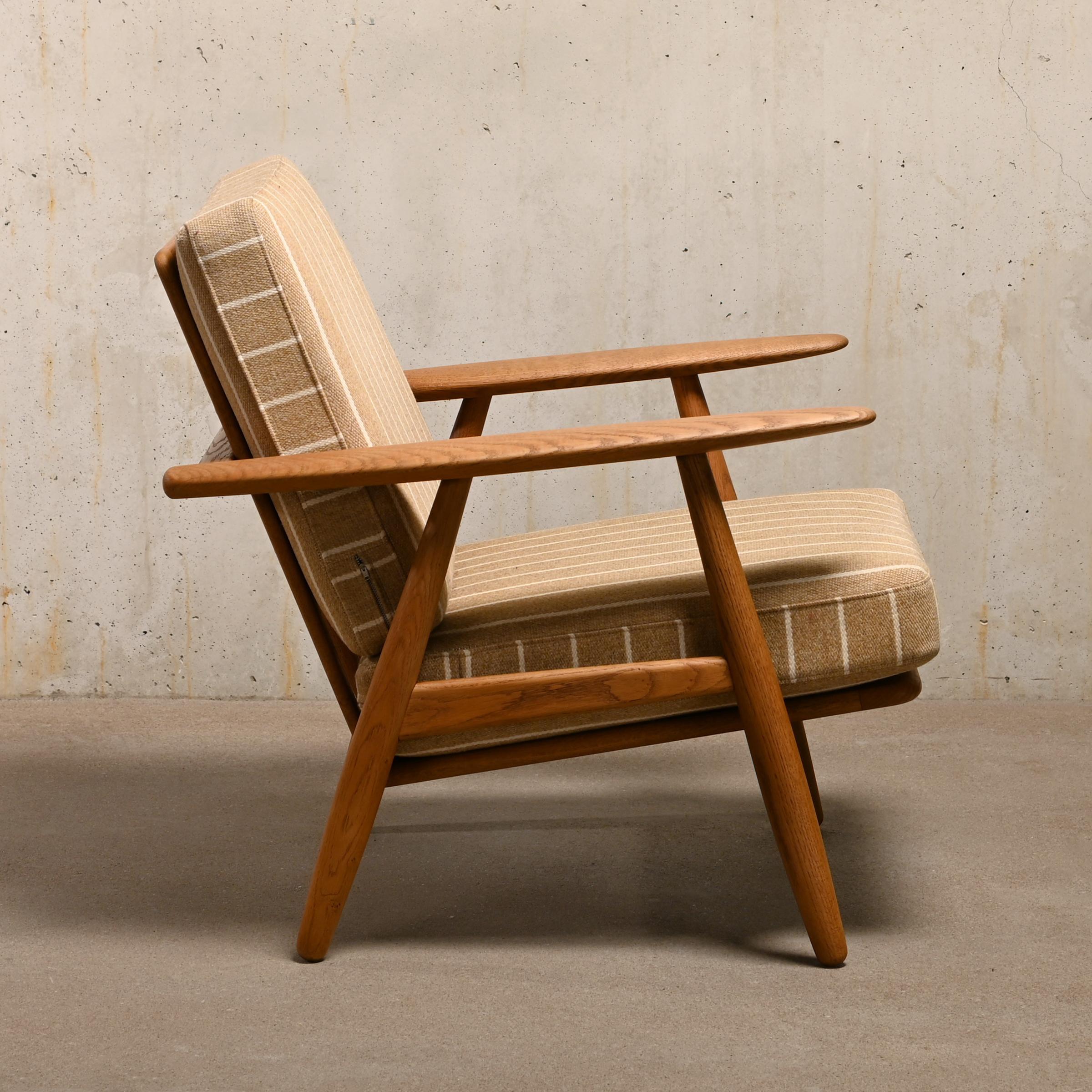 This is an early example of the Hans J. Wegner Lounge Chair model GE240 for GETAMA, Denmark. The chair is also sometimes called Cigar Chair due the shape of the armrests. Beautiful aged and grained high quality oak wooden frame in very good