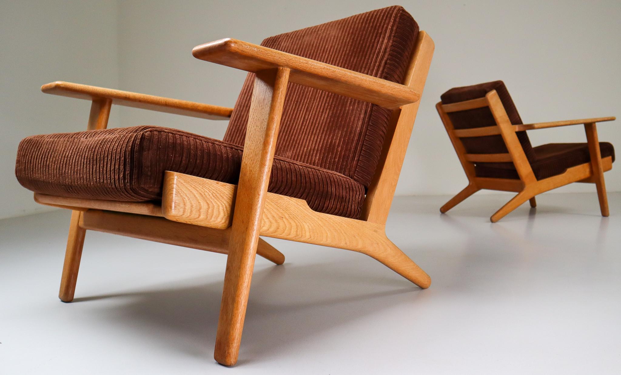 A set of two original iconic Hans J. Wegner GE290 oak framed armchairs Designed in 1954 and produced by GETAMA - Denmark. These pieces features original brown wool upholstery and is in very nice condition and has a nice brown patina. These armchairs