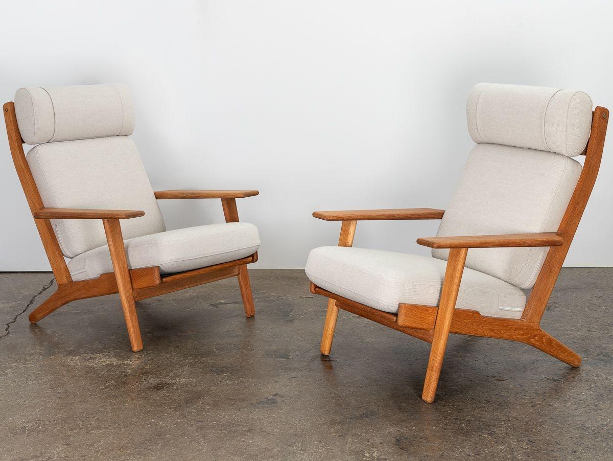 A handsome pair of GE 290A lounge chairs, designed by Hans J. Wegner for Getama. Frames are crafted from beautiful Danish white oak, in a reclining silhouette with a ladder back and brass hardware details. Generously proportioned, this model