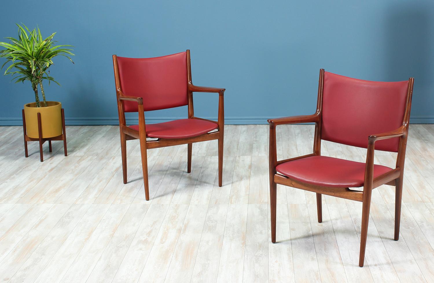 A Pair of JH-509 Armchairs designed by iconic Danish furniture designer, Hans J. Wegner, for Johannes Hansen in Denmark circa 1950's. Originally designed for conference and meeting rooms, this newly refinished pair is sculpted with a solid walnut