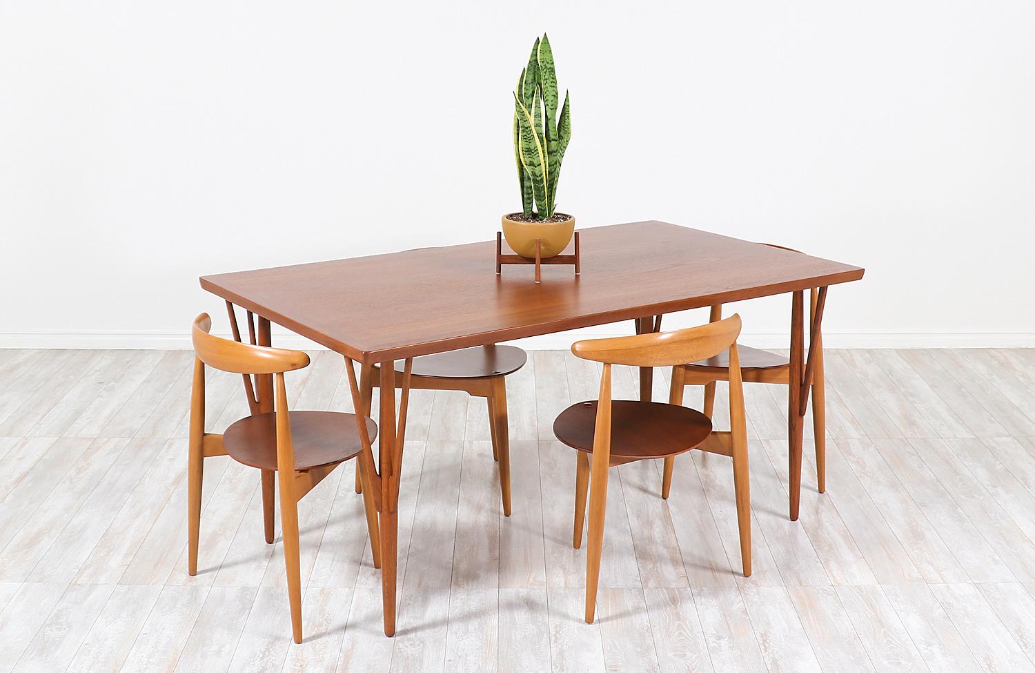 Stylish dining table/desk designed by Hans J. Wegner for Johannes Hansen in Denmark, circa 1950s. This Classic model JH-561 table features a solid teak wood rectangular top and angled legs with stretchers adding a Minimalist and clean modern look.