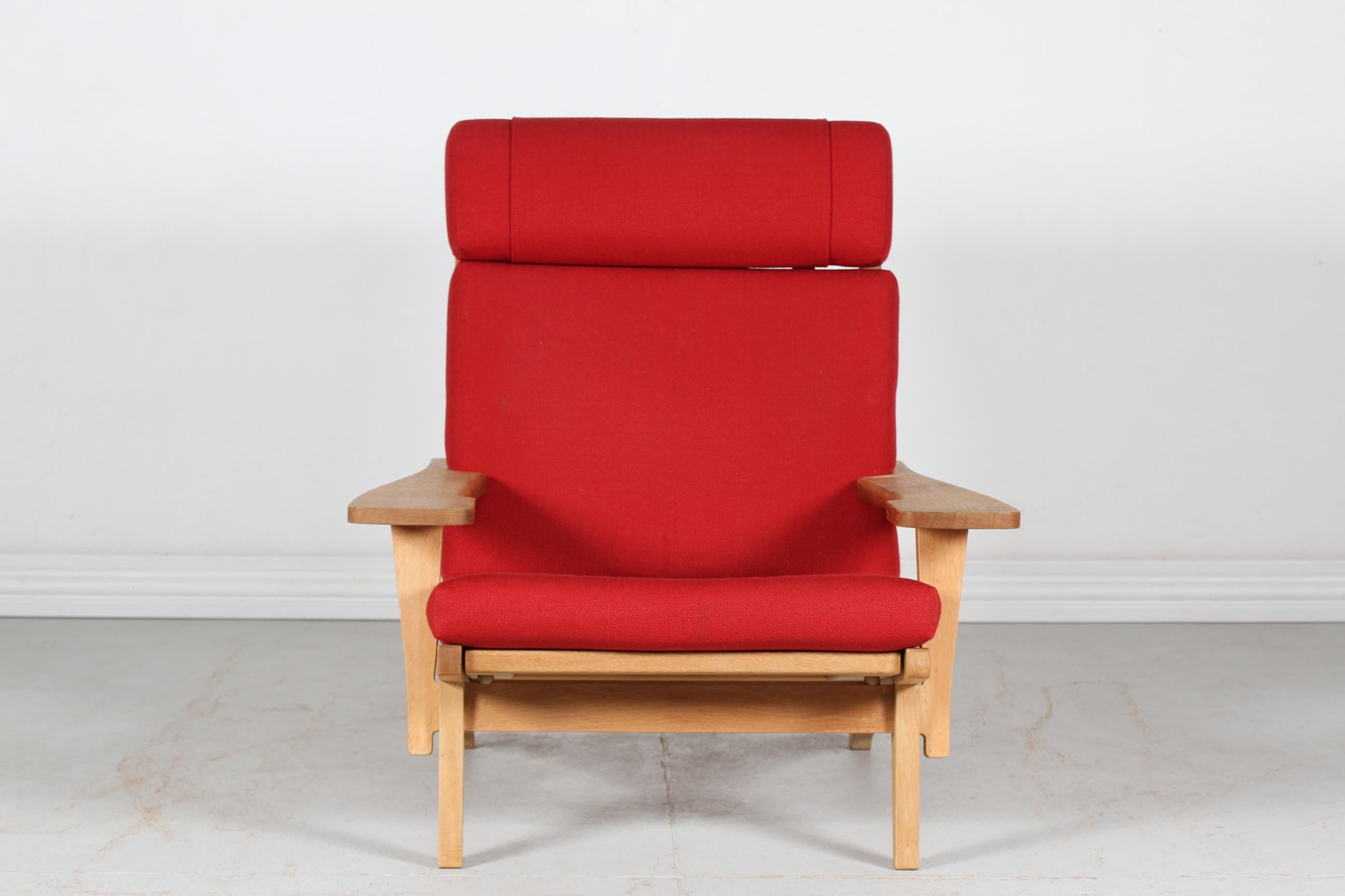 Lounge chair model GE 375 with high backrest by Danish designer Hans J. Wegner (1914-2007) in 1969.
The chair is manufactured in the 1970s and made of solid oak with the original cushions upholstered with red fabric.

Nice vintage condition with