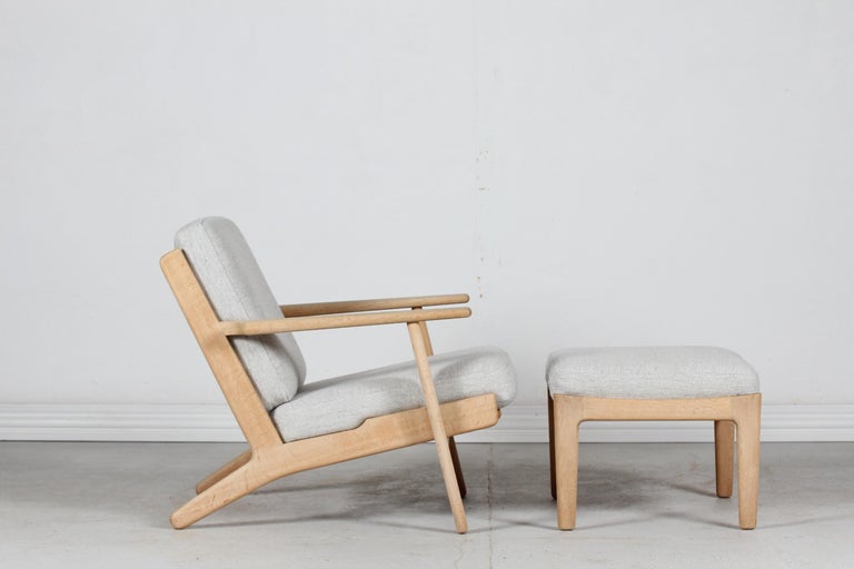 Lounge chair and with matching stool model GE 290 low version by the Danish designer Hans J. Wegner in 1953.
This chair is manufactured in the 1970´s of solid oak with soap treatment.
The relatively new foam cushions are upholstered with light
