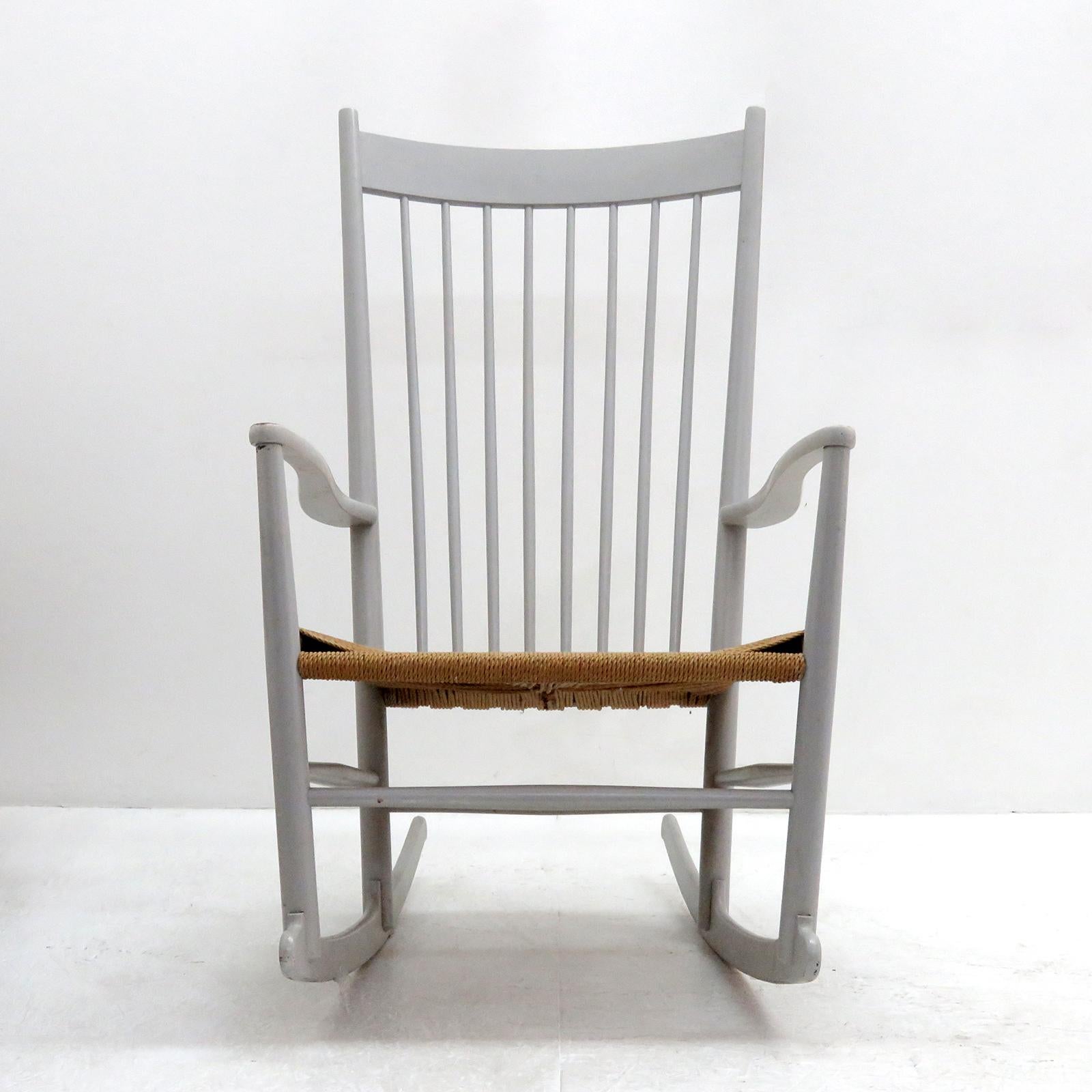 Wonderful model J16 rocking chair by Hans Wegner for FDB Møbler, designed in 1944, in light-gray painted beech with woven paper cord seat. This example was produced in 1961, features a tall spindle back, gracefully curvaceous arms and blade-style