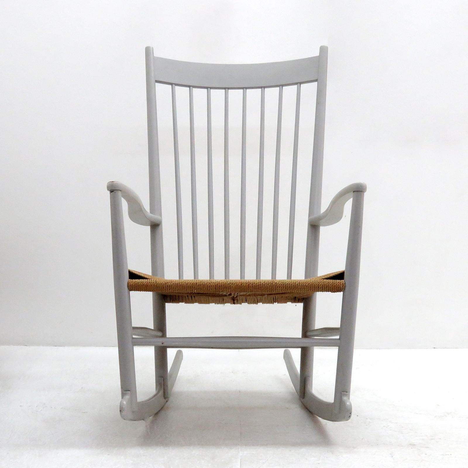 Magnifique fauteuil à bascule modèle J16 de Hans Wegner pour Design/One, conçu en 1944, en hêtre peint en gris clair avec assise en corde de papier tressé. Cet exemple, produit en 1961, présente un haut dossier en fuseau, des accoudoirs aux courbes