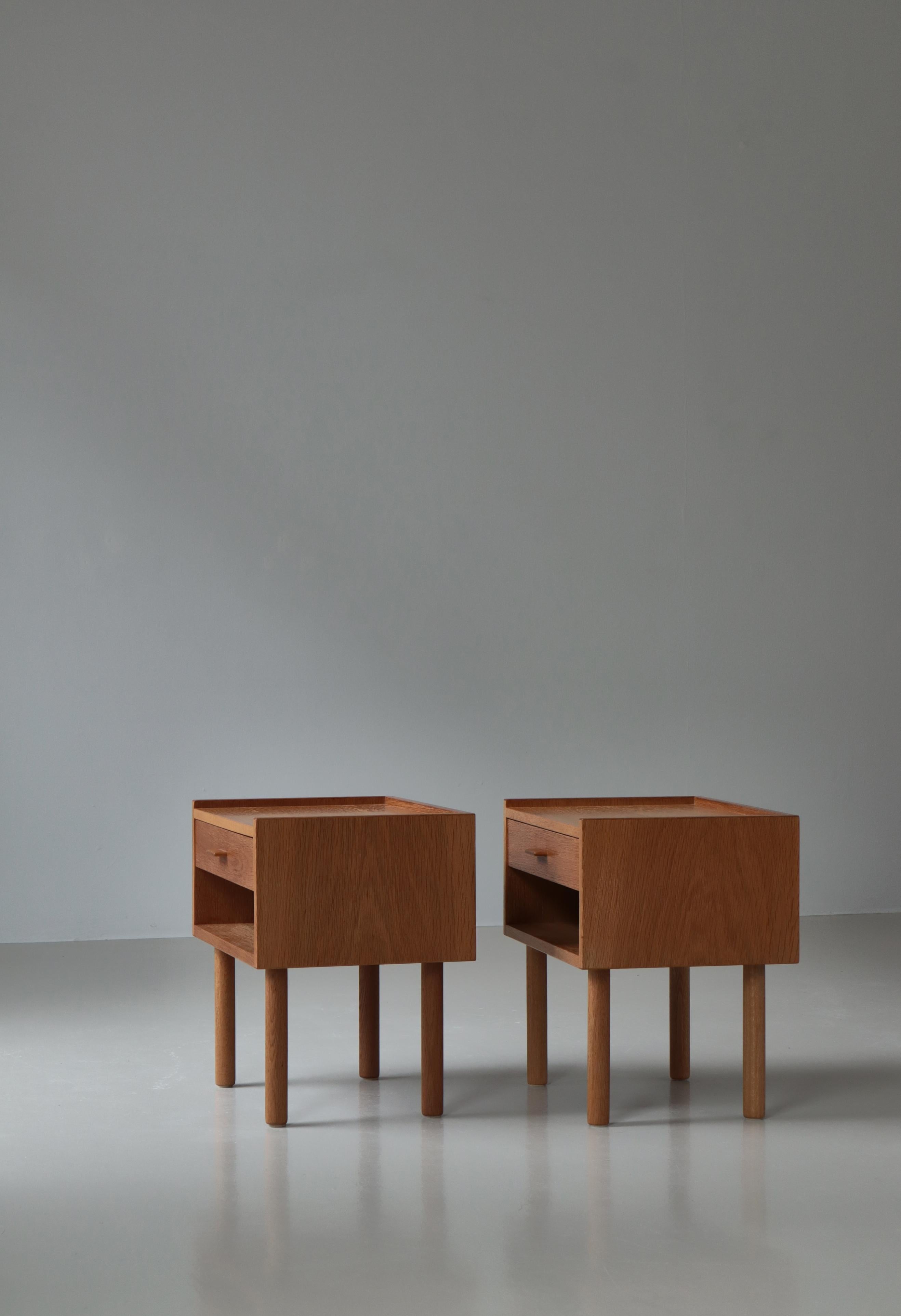 A pair of Danish modern bedside tables from the 1960s by Hans J. Wegner. Made in oakwood by original maker Ry Møbler, Denmark. Typical of Wegner's designs from this period is the minimalistic approach to design and the subtle details. Each table