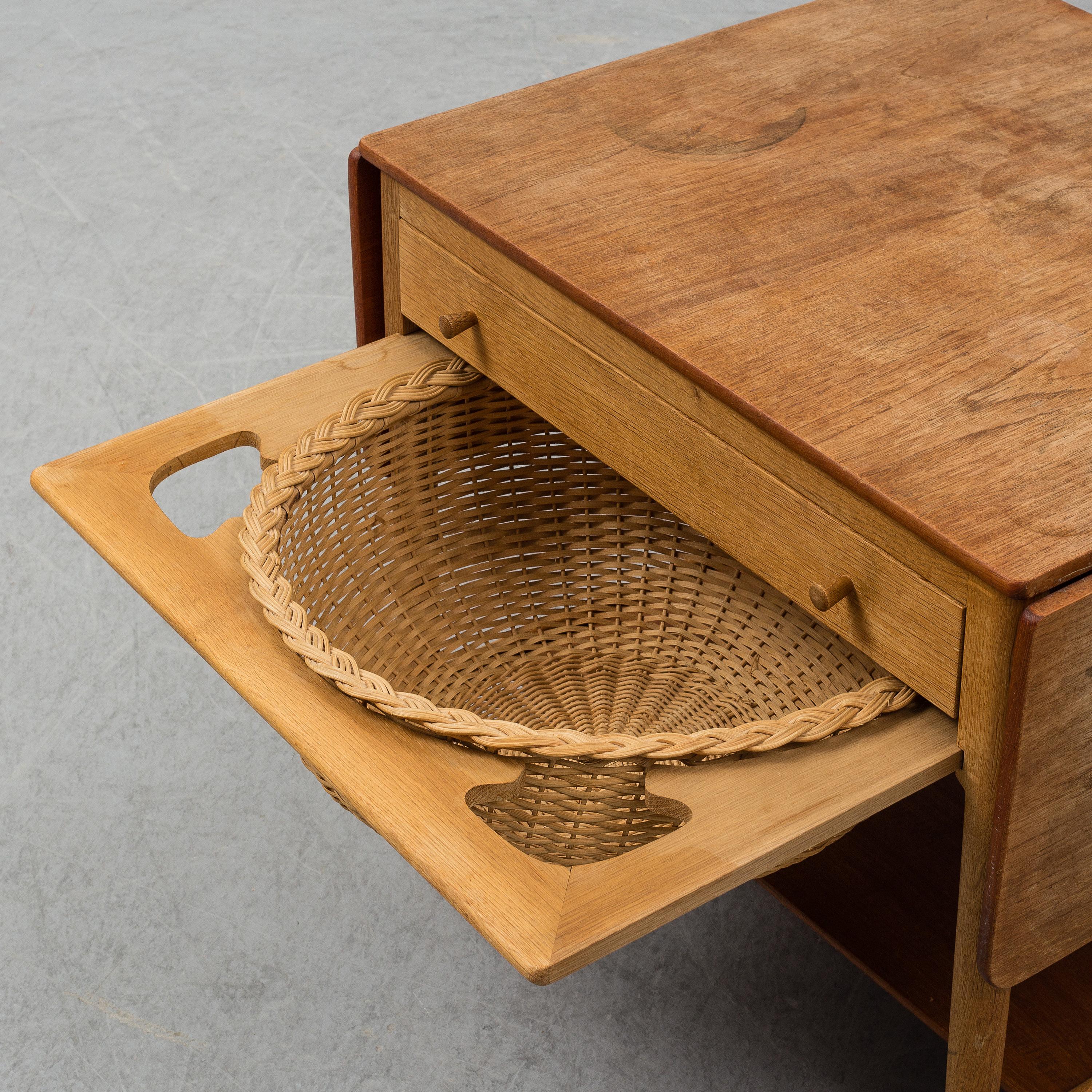 Sewing table AT-33 by Hans J Wegner, made by Andreas Tuck, Denmark, circa 1950s. This solid oak sewing table, designed by Hans J Wegner and made by cabinetmaker Andreas Tuck. The table features two flaps, a front drawer with several compartments and