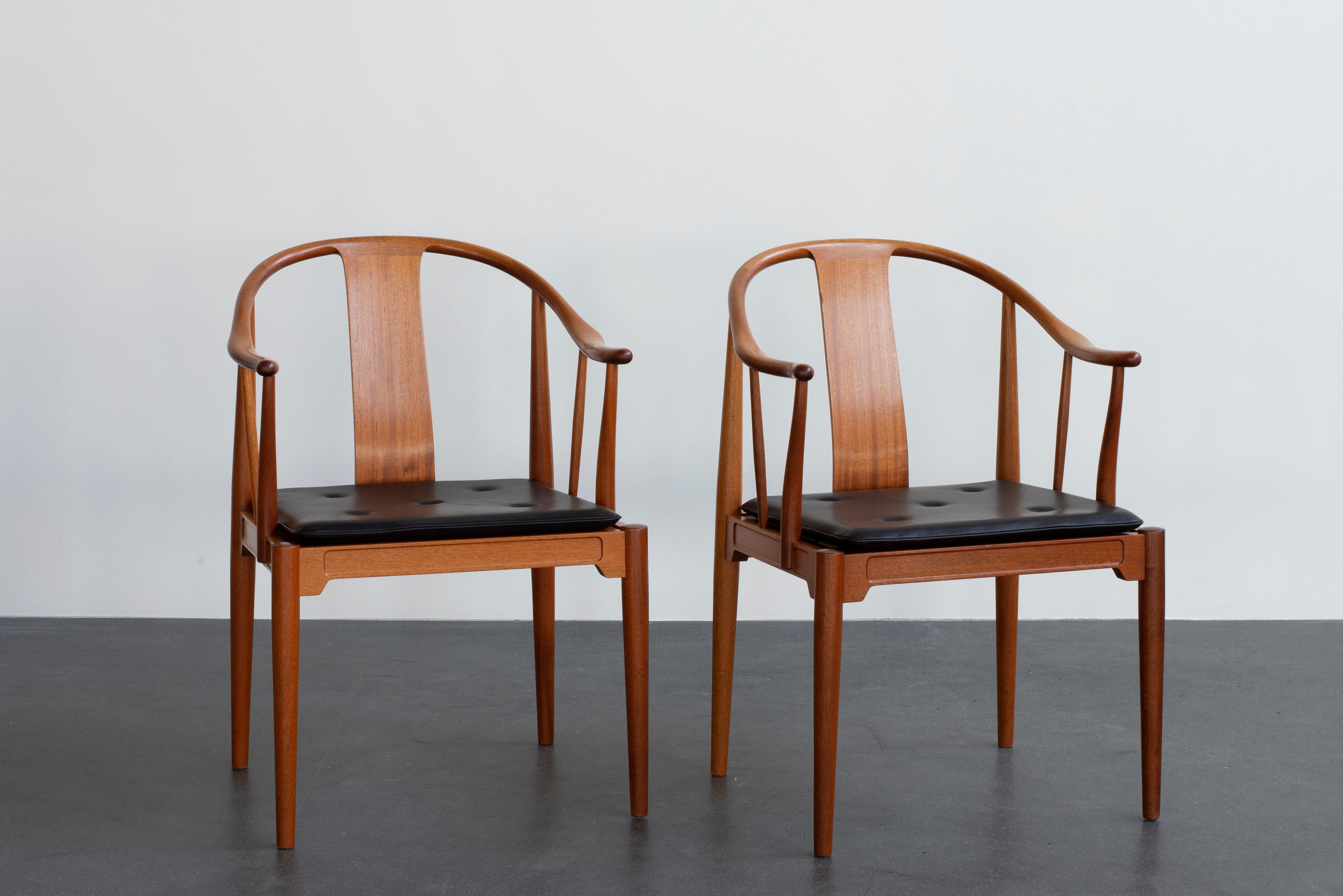 Hans J. Wegner Chinese chairs in mahogany. Loose seat cushions upholstered with leather, fitted with buttons. Executed by Fritz Hansen.

