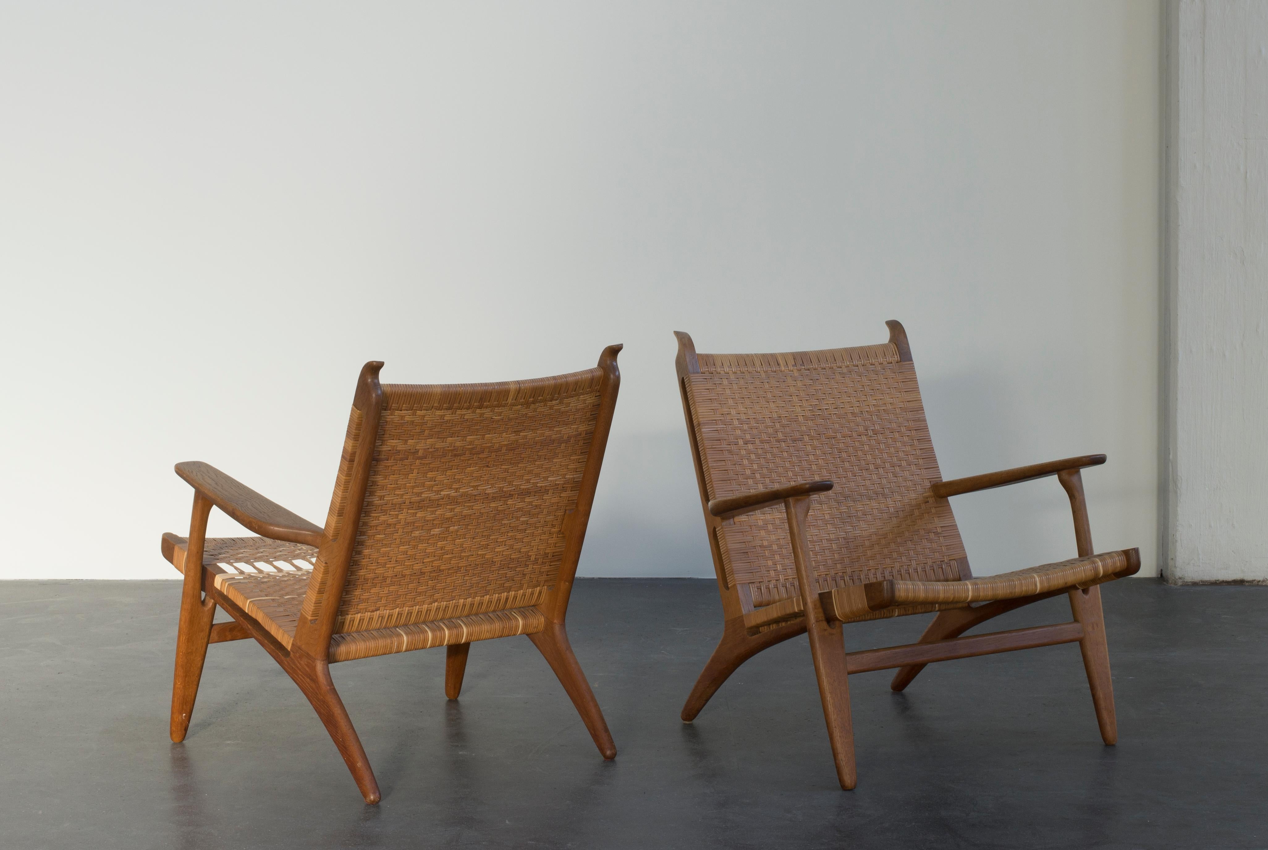 Hans J. Wegner pair of easy chairs with oak frames. Seat and back with woven cane. Executed by Carl Hansen & Søn.