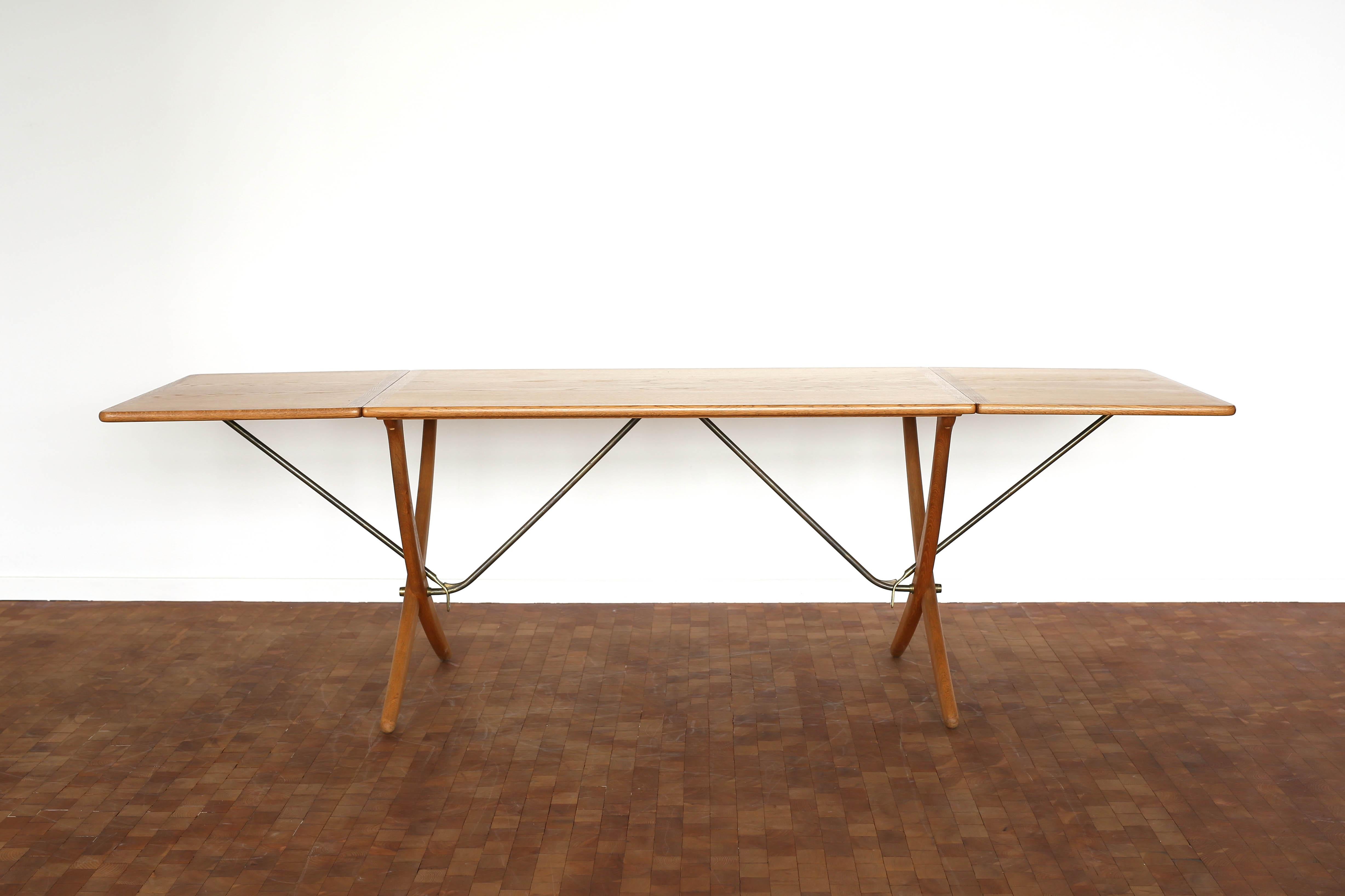 Hans J. Wegner oak dining table with two drop-leaves and cross-legs, stretchers of brass. Very fine condition. 

Designed by Wegner 1950 and manufactured by cabinetmaker Andreas Tuck, Denmark, model AT304. Marked by Maker. 

Measuring 128 cm /50