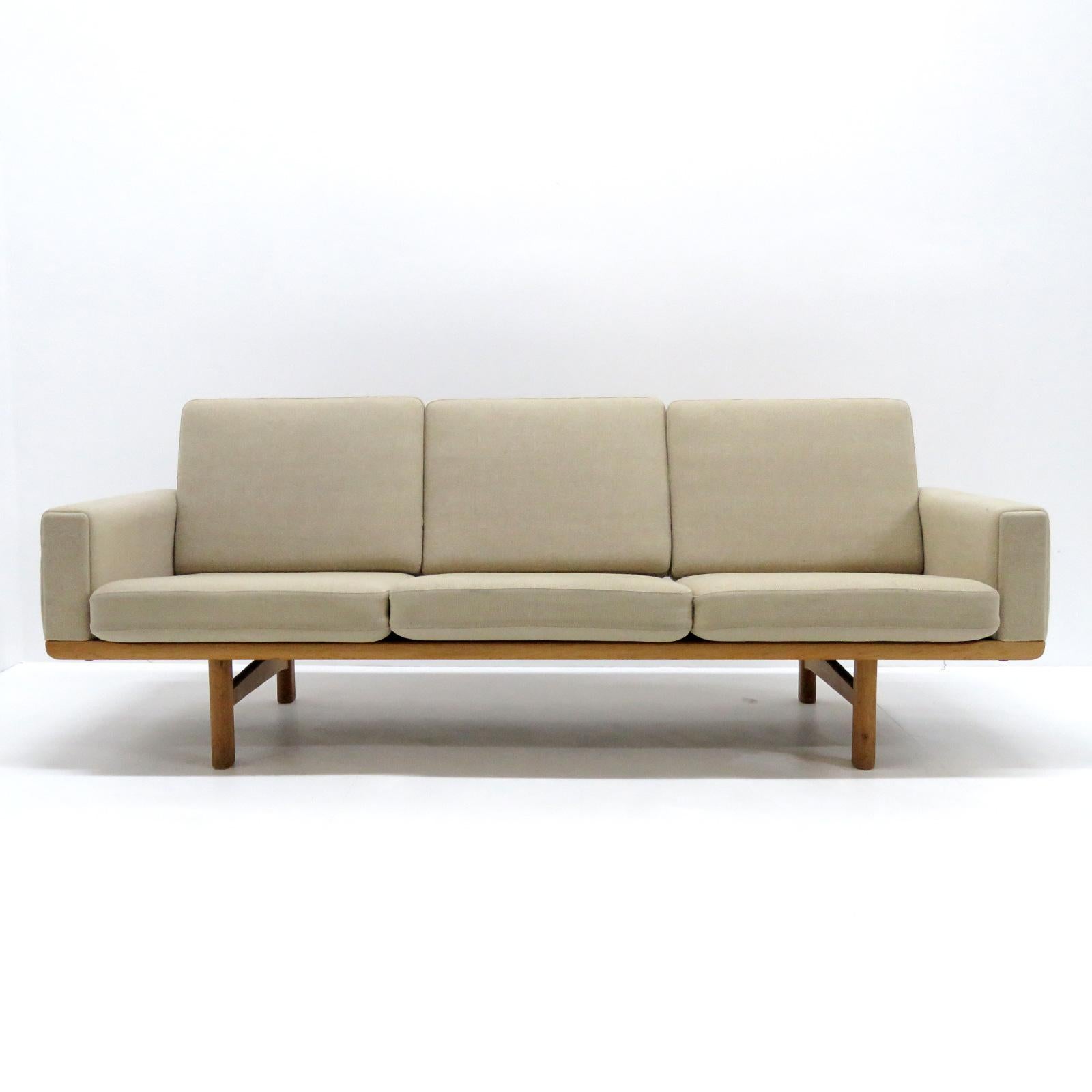 Vintage 1950s Danish three-seat sofa, model GE236/3 designed by Hans J. Wegner for GETAMA, solid oak frame with nice patina and original spring loaded cushions later reupholstered with light beige wool fabric, marked.