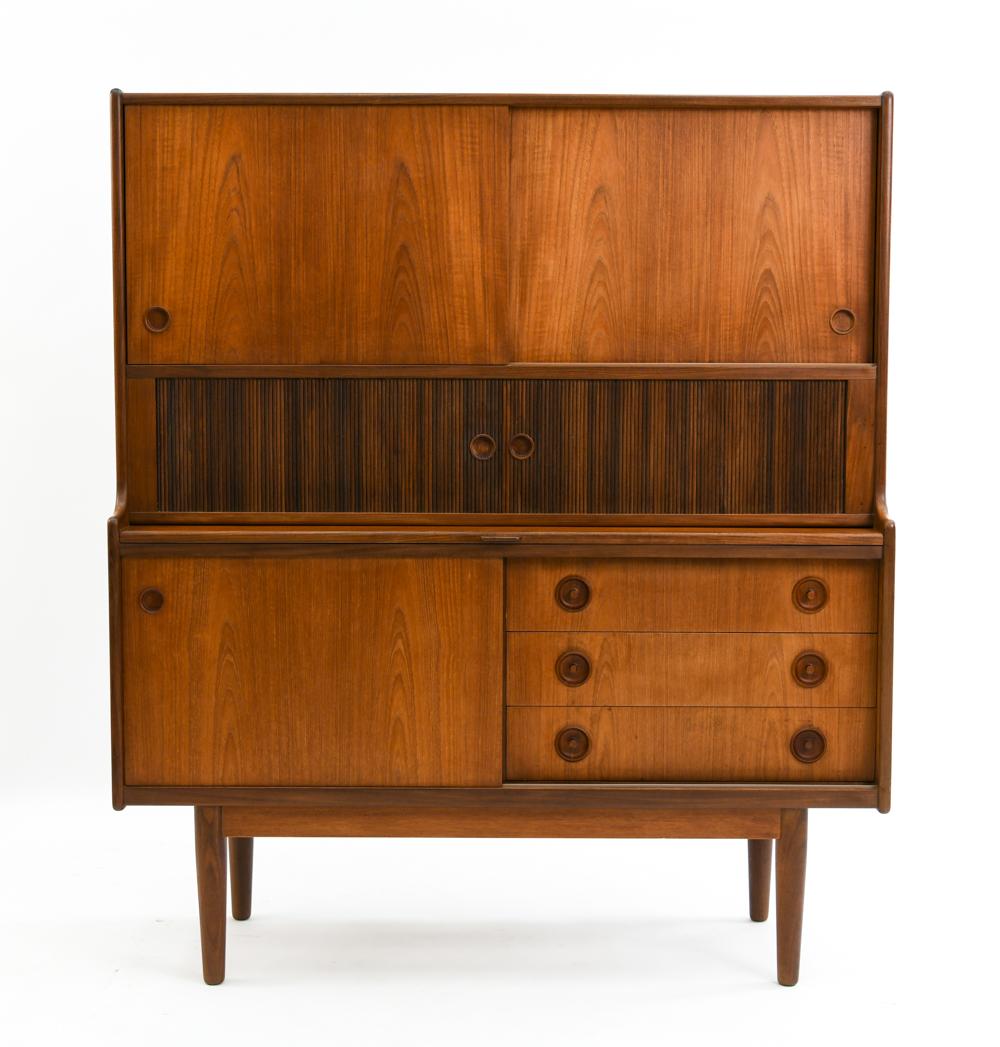 A fine quality Danish modern teak highboard. Featuring a gorgeous patina with lovely wood graining. The two top sliders open to reveal one large adjustable shelve as well as three small felted drawers. The middle tambour slides open to reveal one