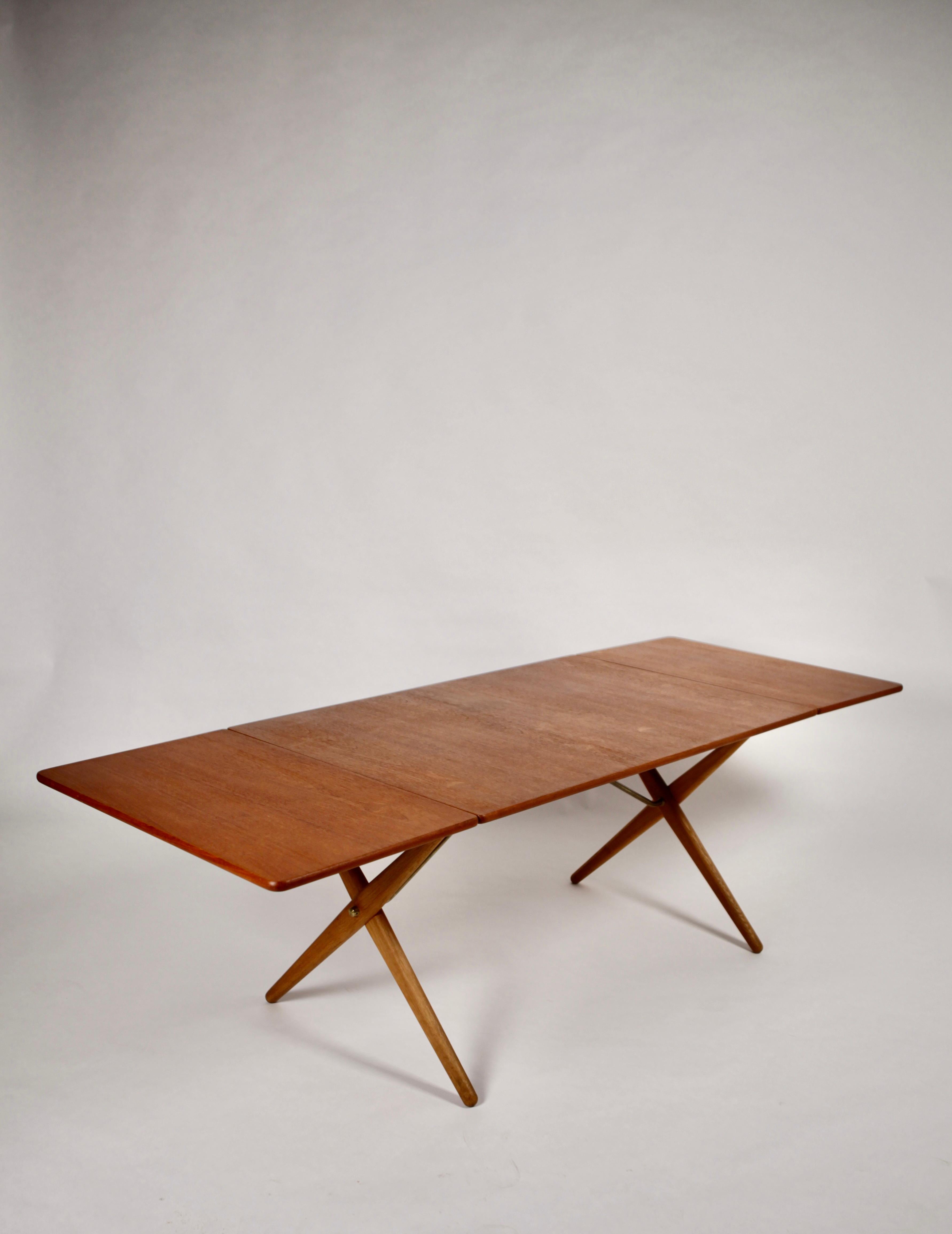 Hans J. Wegner, dining-table, model AT-303.
Cross-leg dining table, designed by Hans J. Wegner for Andreas Tuck, executed in Teak, Oak & Brass, also known as Sawhorse table, the design is beautiful and functional. 
Drop leaves extend to seat up to