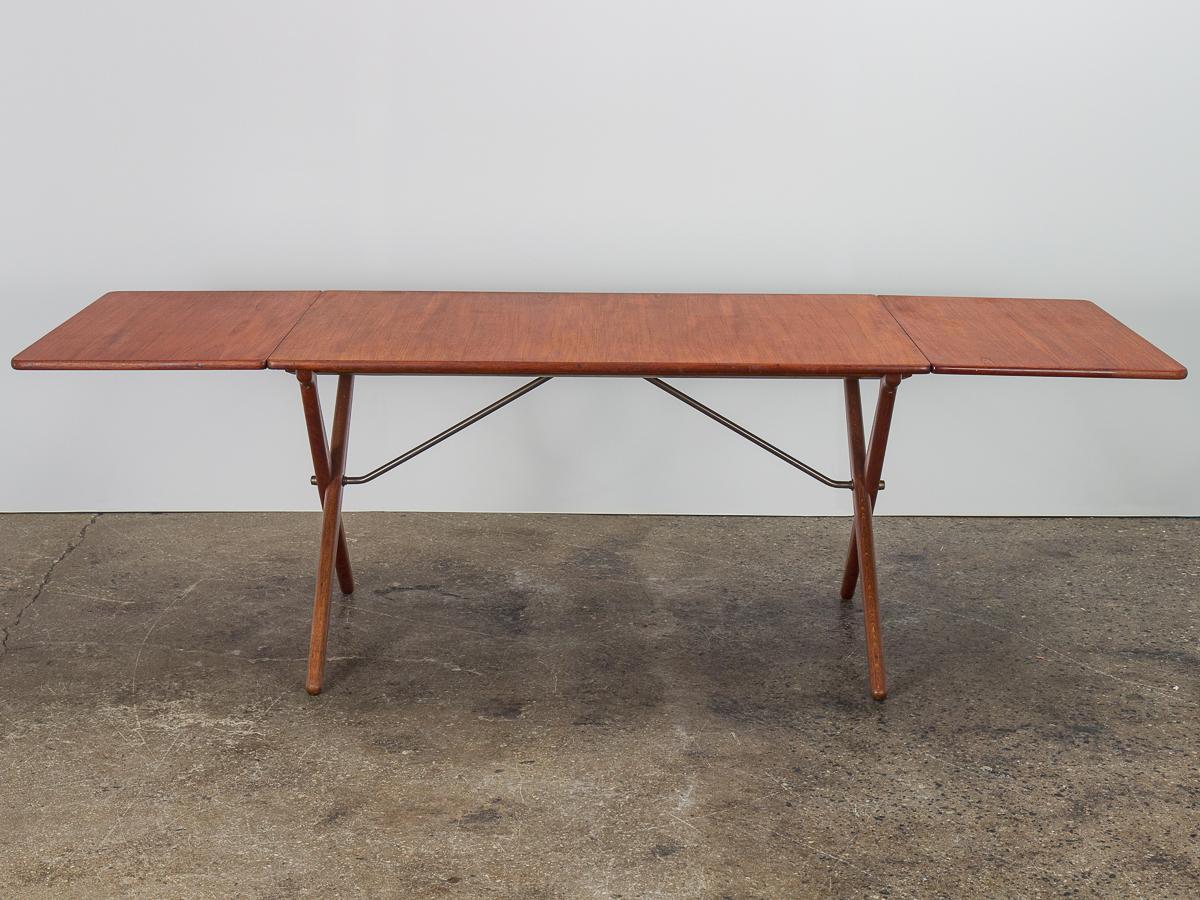 Scarce teak model AT-303 cross-leg dining table, designed by Hans J. Wegner for Andreas Tuck. An iconic form also known as the Sawhorse table, the design is beautiful and functional. Distinct cross-shaped legs in a stained oak make a graphic