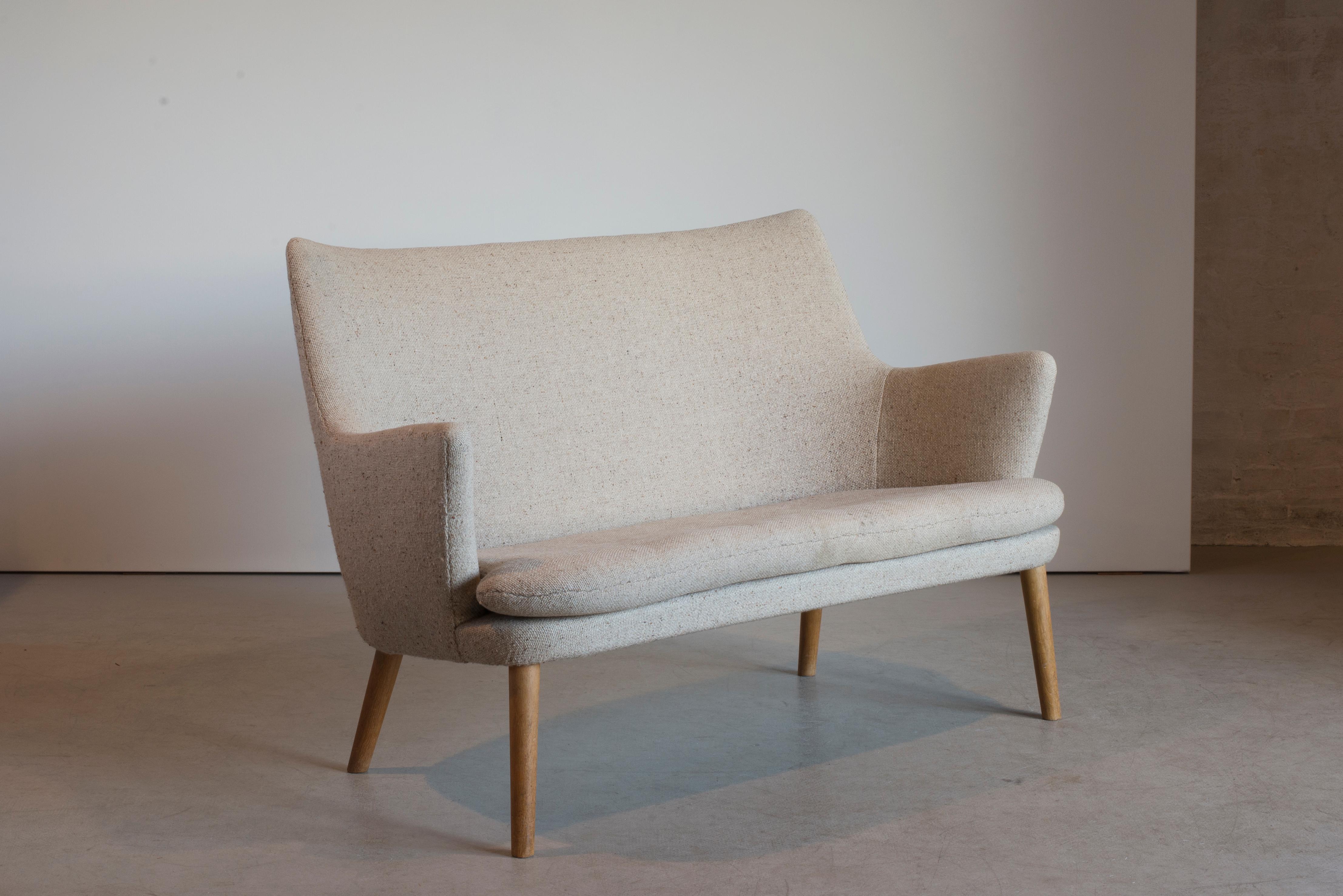 Hans J. Wegner two-seat sofa in oak and fabric. Executed by AP Stolen, Denmark.
 
