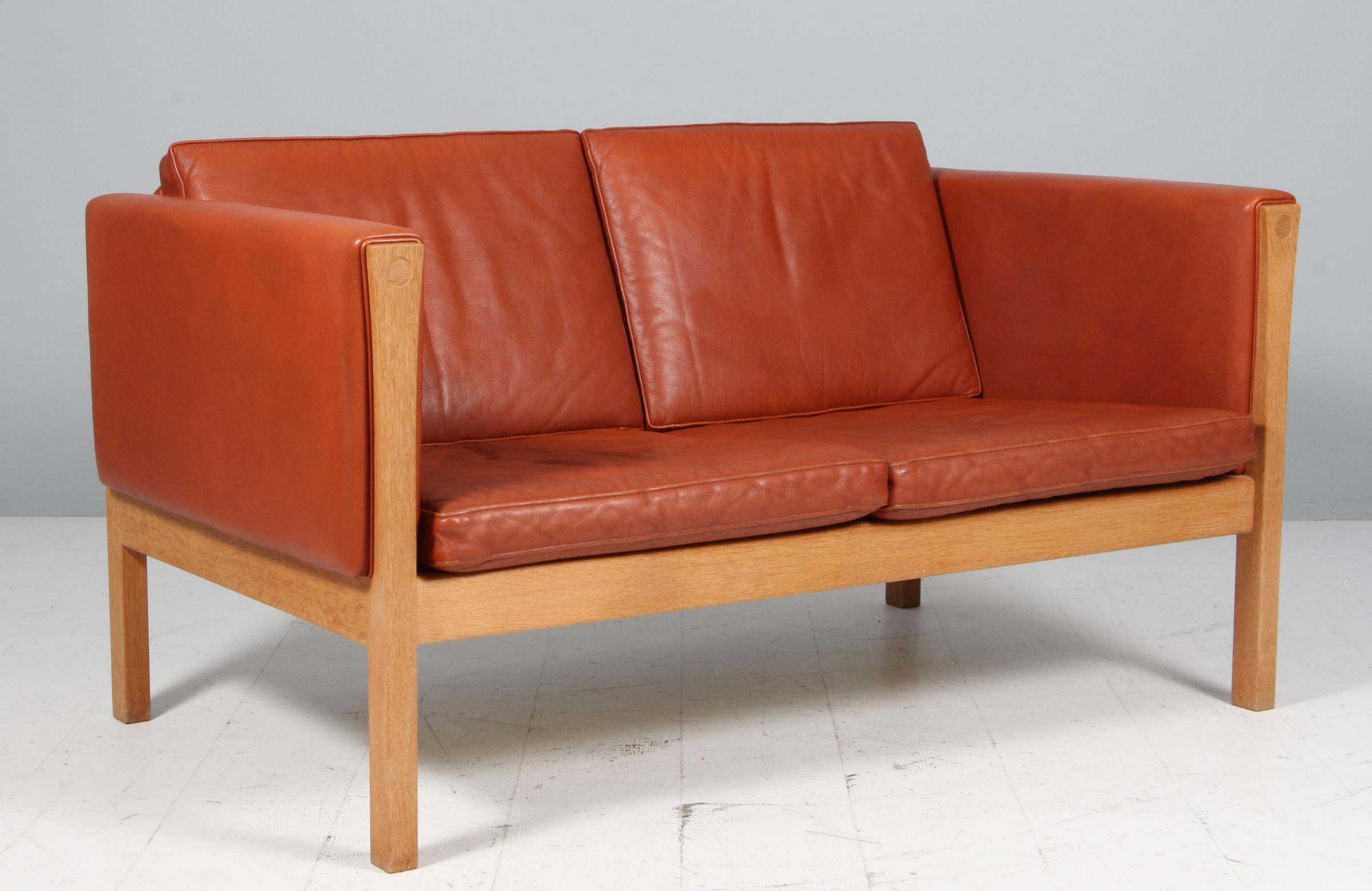 Canapé deux places Hans J. Wegner, tapissé d'origine en cuir cognac.

Cadre en chêne massif.

Modèle AP 62/2, fabriqué par AP.