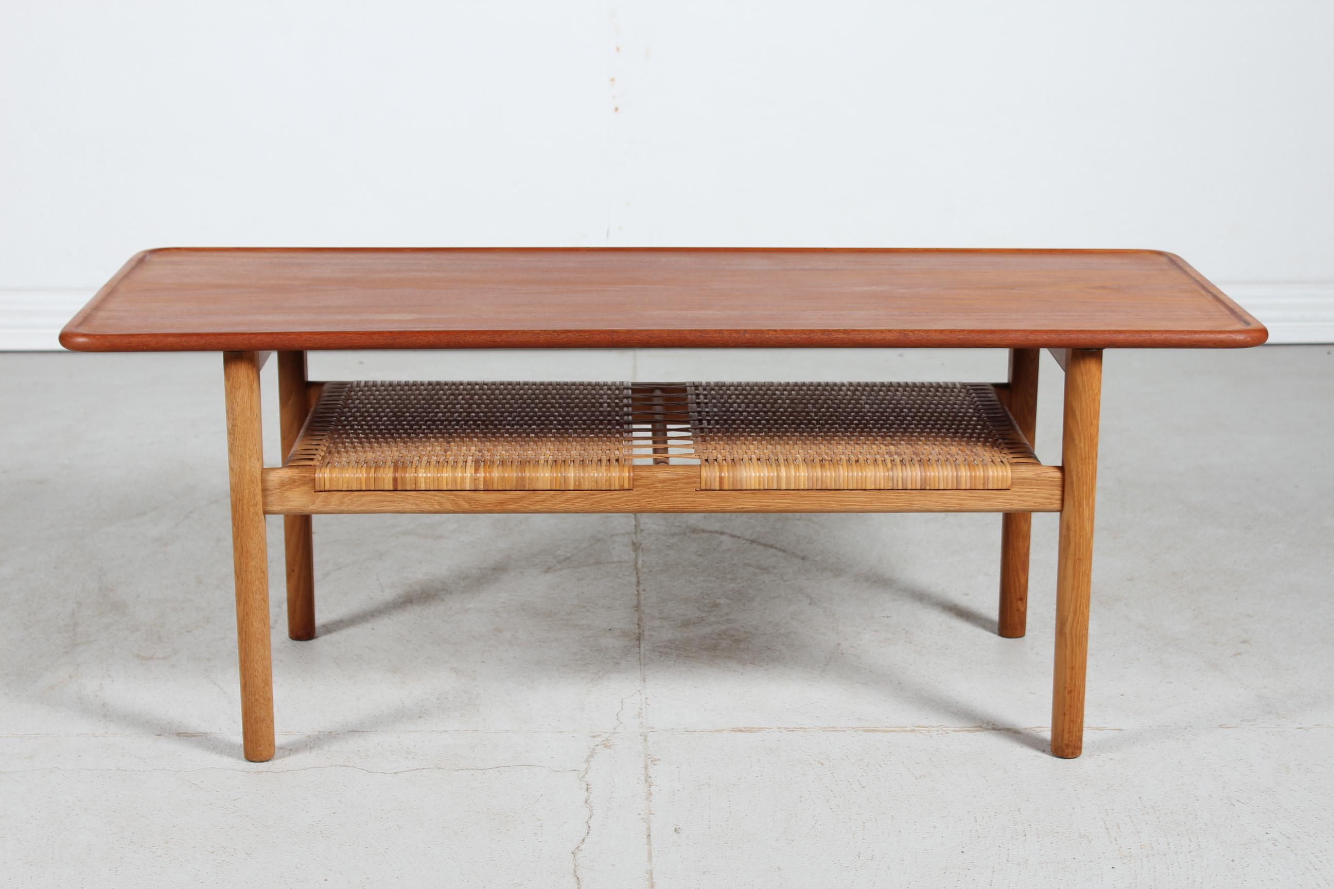 Vintage coffee table model AT 10 by Danish architect Hans J. Wegner (1914-2007) manufactured by Andreas Tuck in the 1950s.

The coffee table has a tabletop of solid teak with raised edge mounted on a frame of solid oak. 
Under the tabletop is a