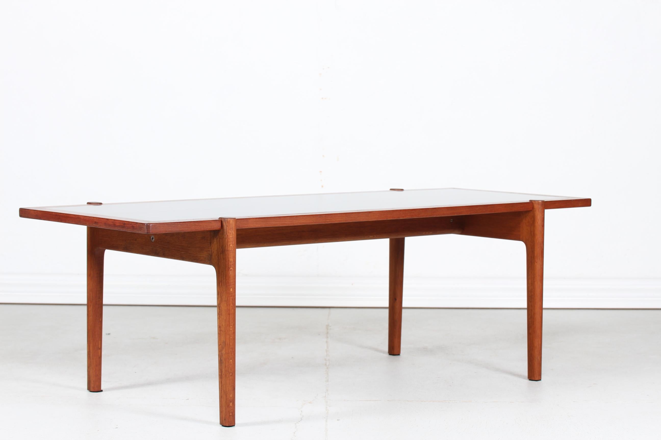 Coffee table by the Danish architect Hans J. Wegner (1914-2007) and manufactured by Johannes Hansen, Copenhagen.
The coffee table has a reversible tabletop made of teak with inlaid black formica on one side. 
The frame is made of oak with