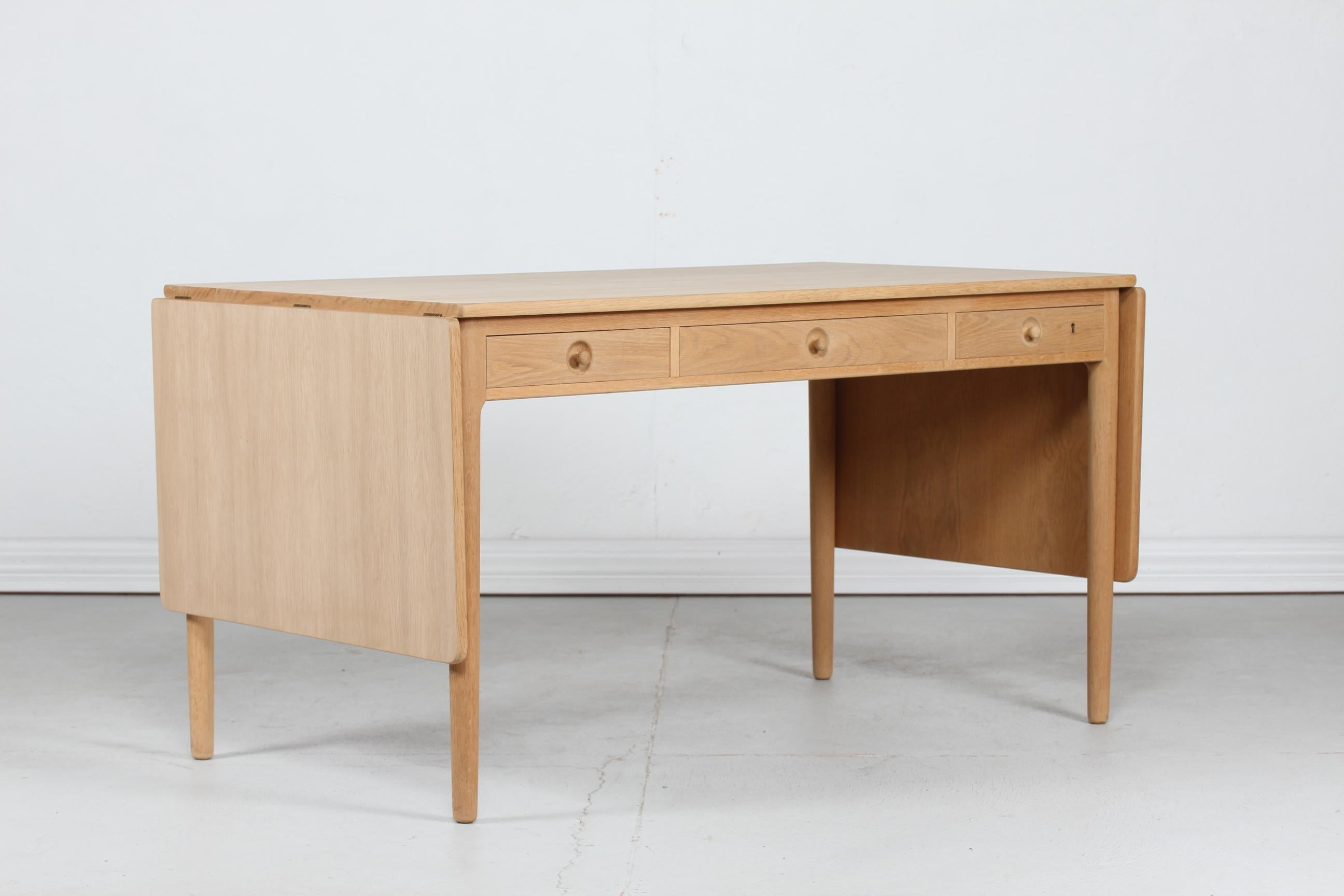 Schreibtisch Modell AT 305 des dänischen Architekten Hans J. Wegner, hergestellt von Andreas Tuck in den 1960er Jahren in Dänemark.
Das Gestell ist aus massivem, unbehandeltem Eichenholz gefertigt und die Tischplatte ist mit neuem, ebenfalls