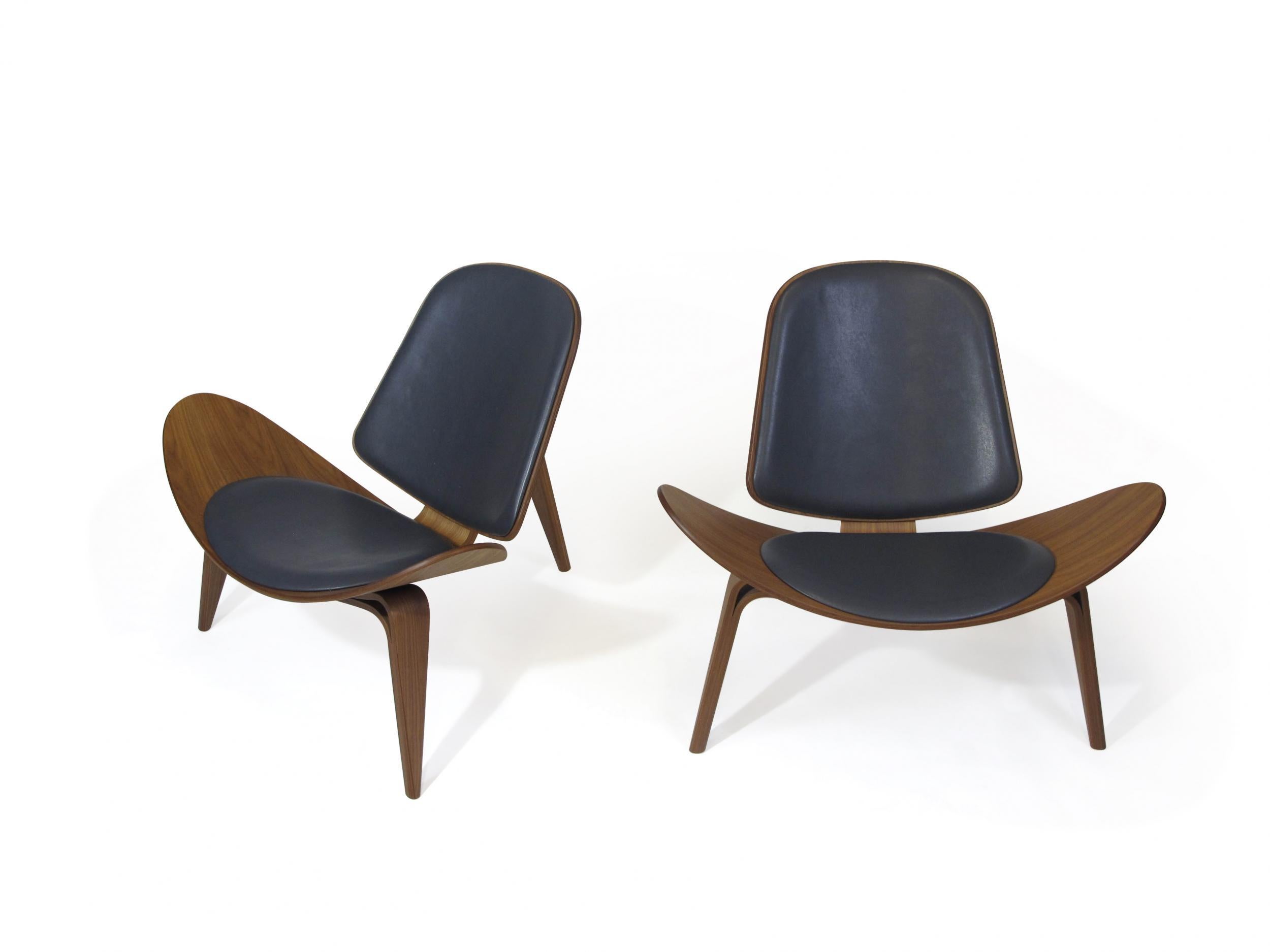 Pair of Hans Wegner shell chairs for Carl Hansen & Son model CH 07. Chairs are crafted of bentwood walnut, with upholstered seats and backs in black leather. The chair has a Carl Hansen label with a serial number attached underneath the