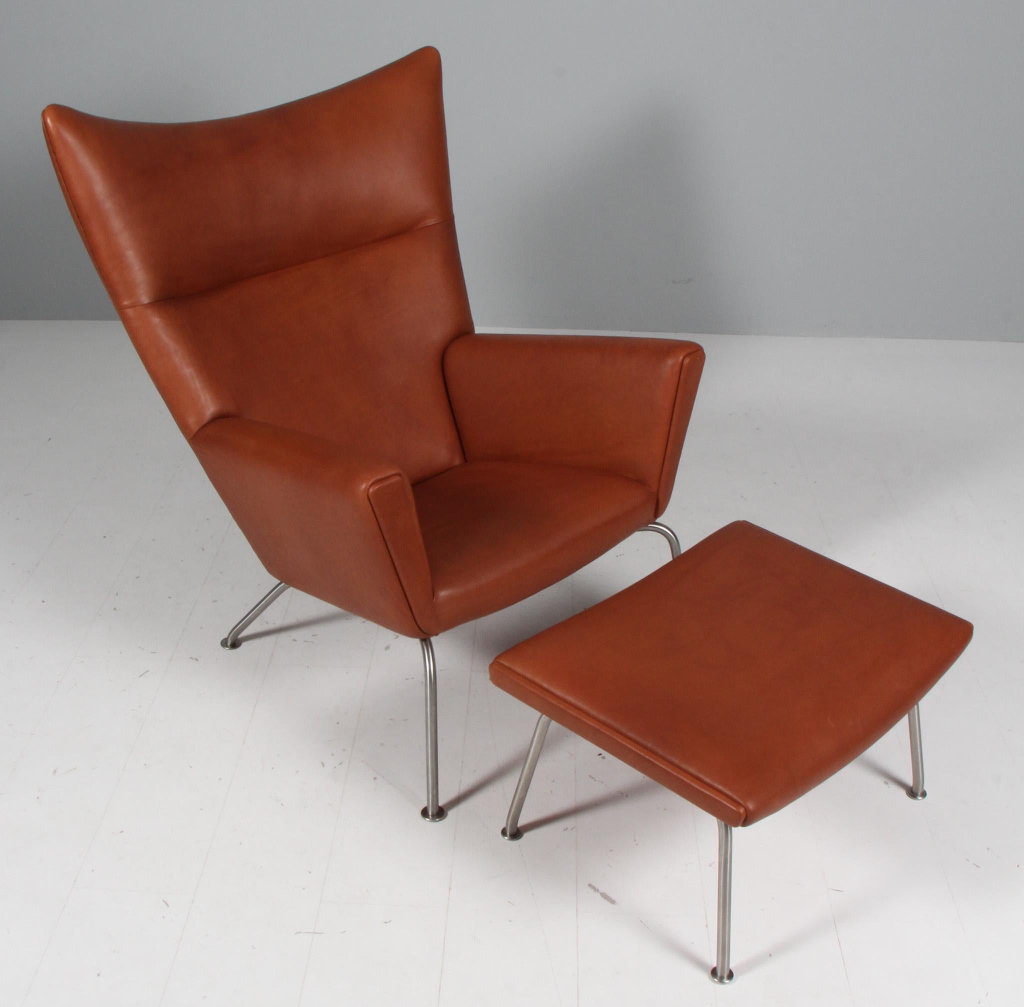 Hans J. Wegner lounge chair / wing chair and ottoman new upholstered with full grain aniline leather.

Frame of brushed steel. 

Model CH448, made by Carl Hansen