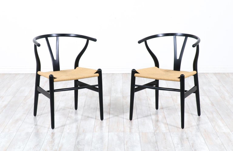 Pair of CH-24 arm chairs designed by Hans J. Wegner for Carl Hansen & Søn in Denmark in 1950. Often referred to as the ‘Wishbone’ chair or the ‘Y’ chair, this iconic design with Chinese influences, features an ebonized wood frame and the new rush