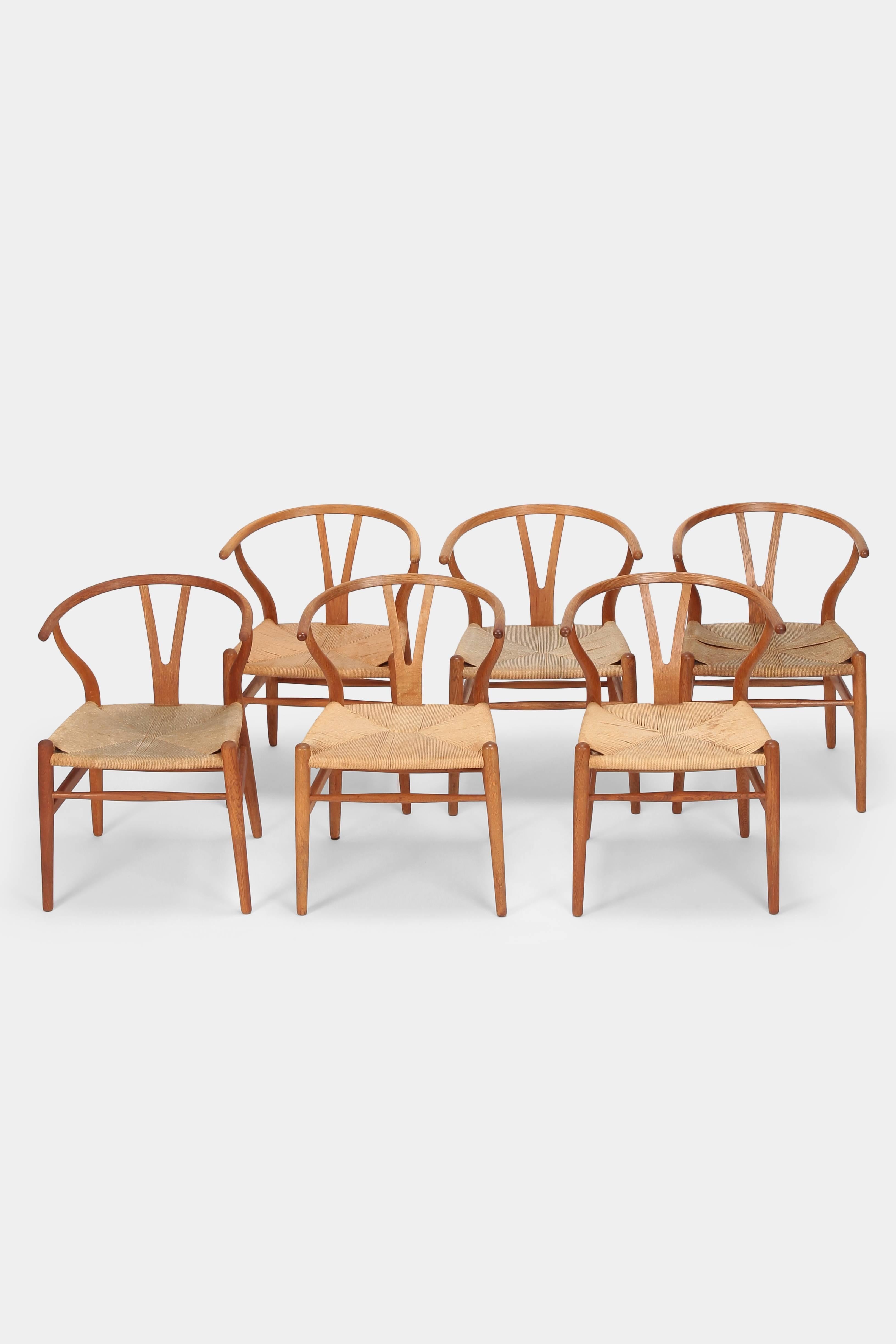 Hans J. Wegner “Y-Chairs” model CH24 manufactured by Carl Hansen & Son in the 1950s in Denmark. Six so called “Wishbone Chairs” with a solid oak wood frame and cord seats. Manufacturer stamp on the bottom. The seat of the chairs have different